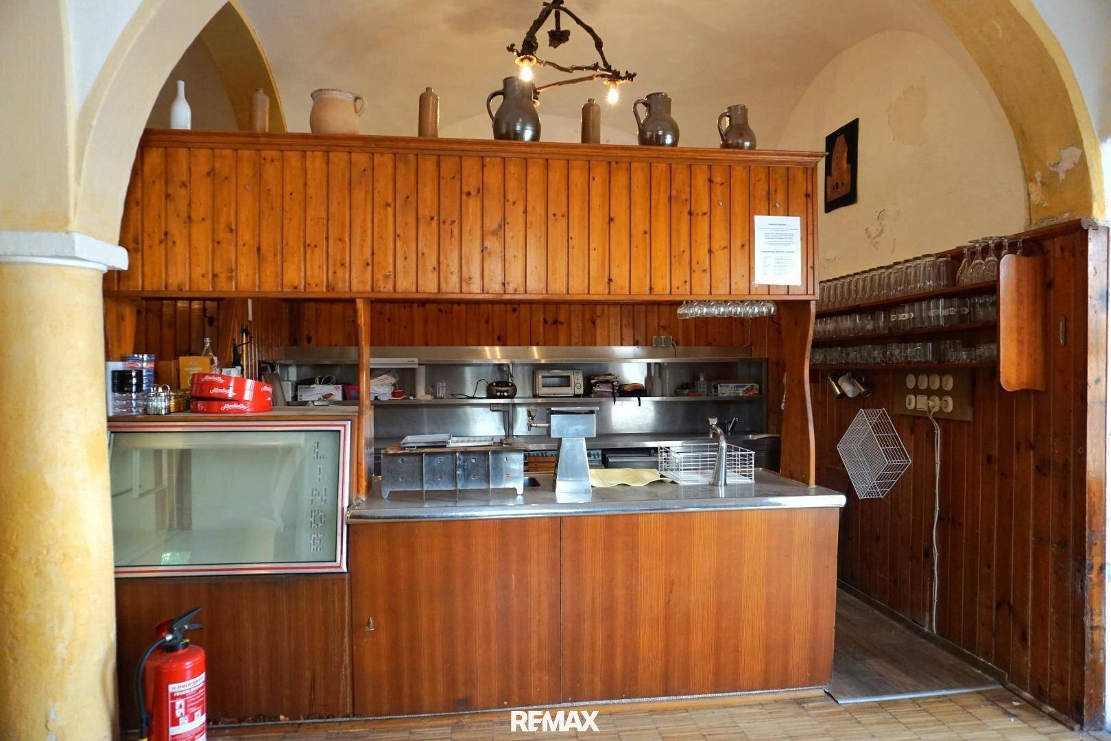 Funktionale Gewerbeküche mit Edelstahltheke, Holzschränken und professionellen Geräten für den Gastronomiebetrieb.