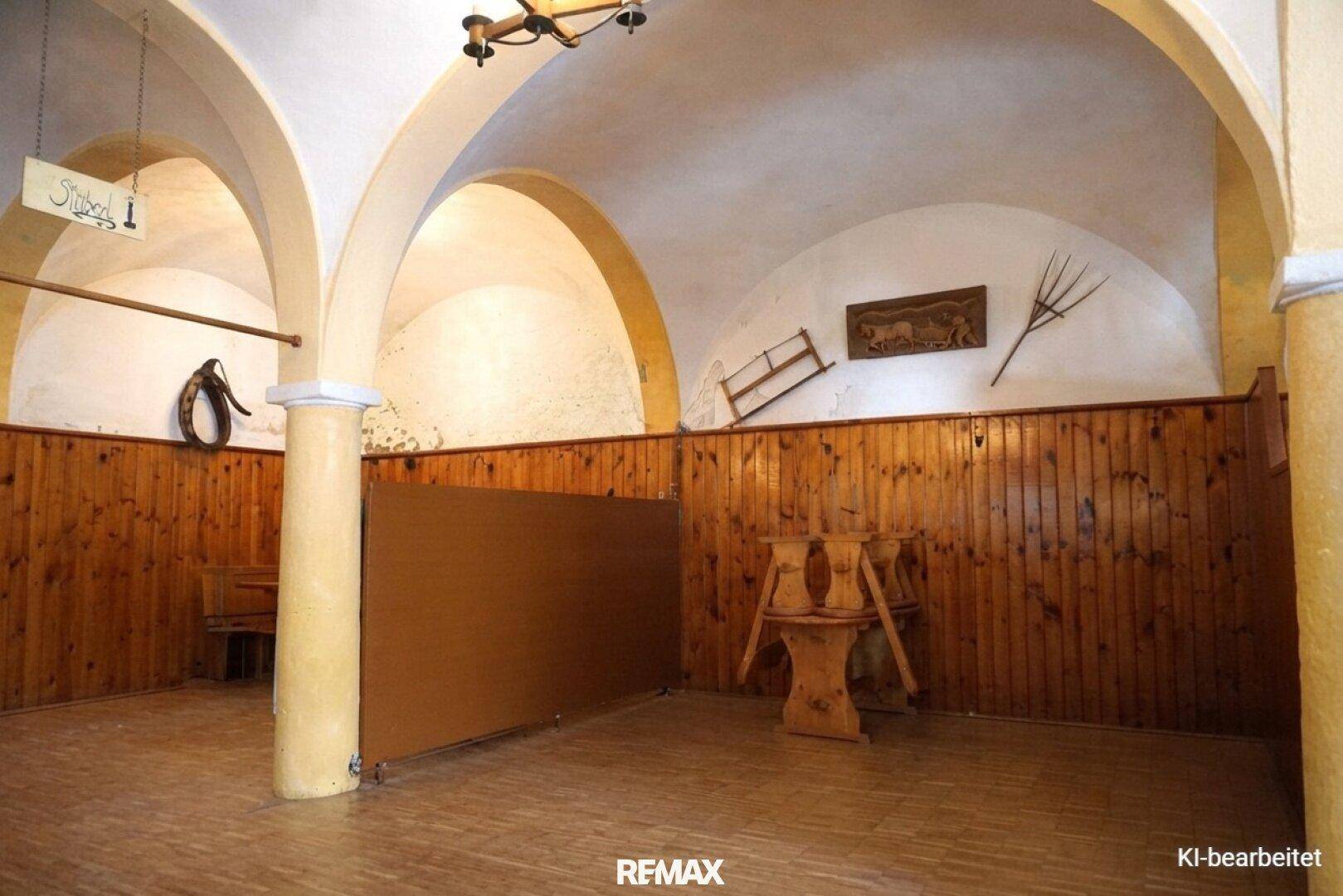 Rustikaler Innenraum mit gewölbten Decken, Holzvertäfelung und traditionellen Dekorationen an den Wänden.