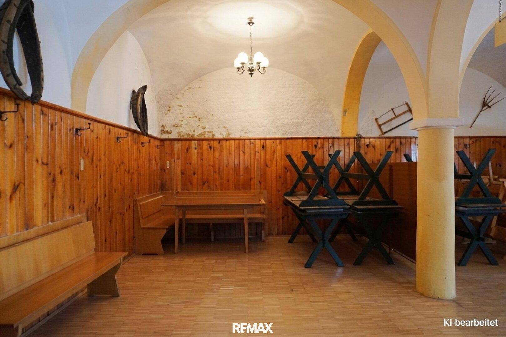 Großer Saal mit gewölbten Decken, Holzvertäfelung und gestapelten Tischen, bereit für Veranstaltungen.