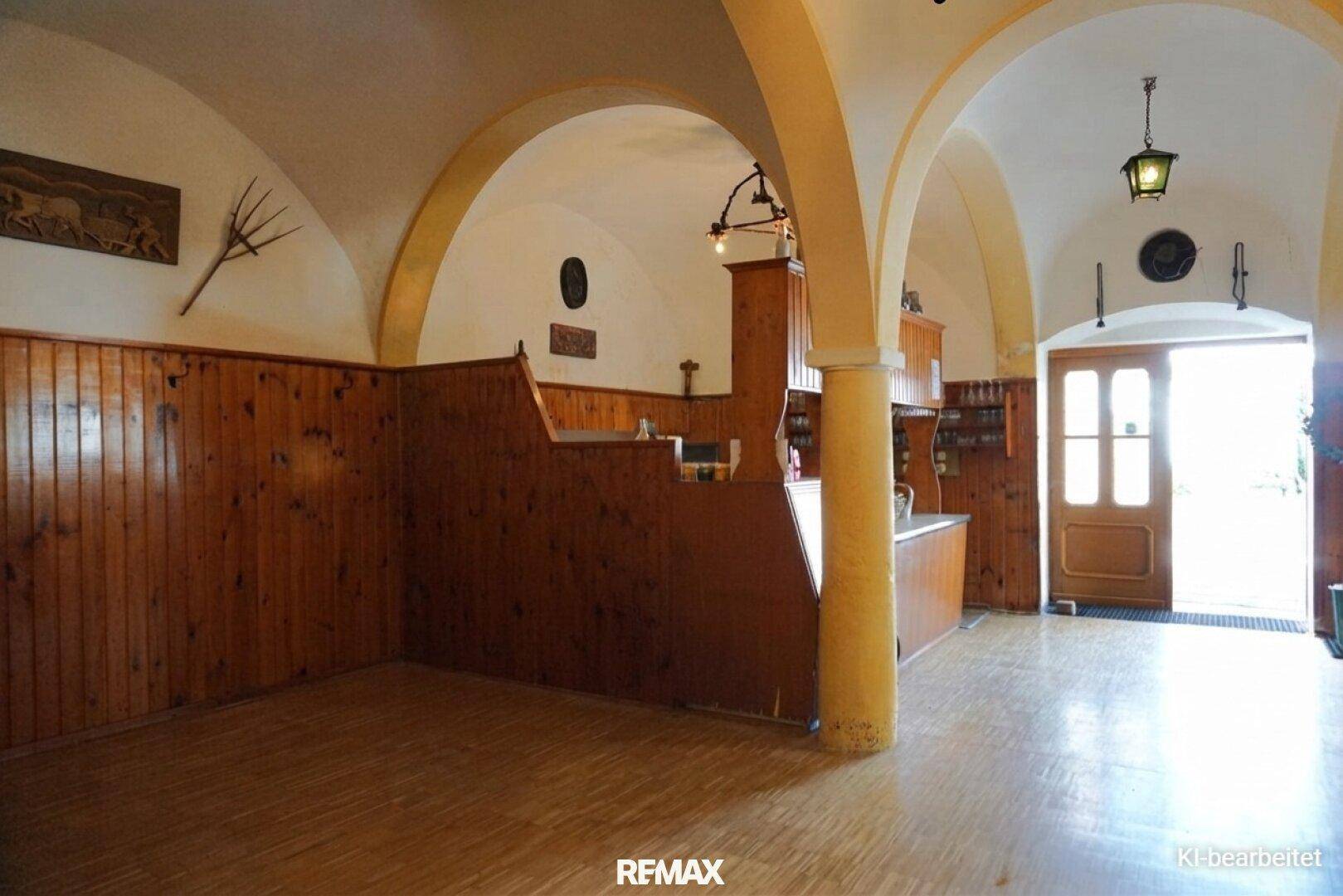 Geräumiger Saal mit gewölbten Decken, Holzvertäfelung und einem Barbereich, der zum Verweilen einlädt.