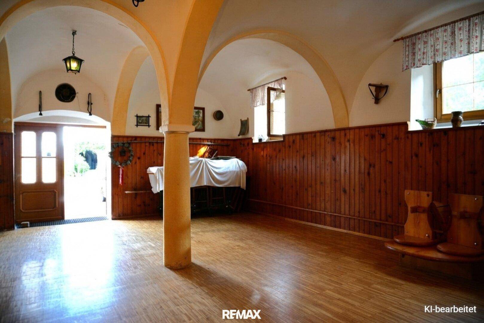 Heller Saal mit gewölbten Decken, Holzboden und einem gedeckten Tisch, der eine einladende Atmosphäre schafft.