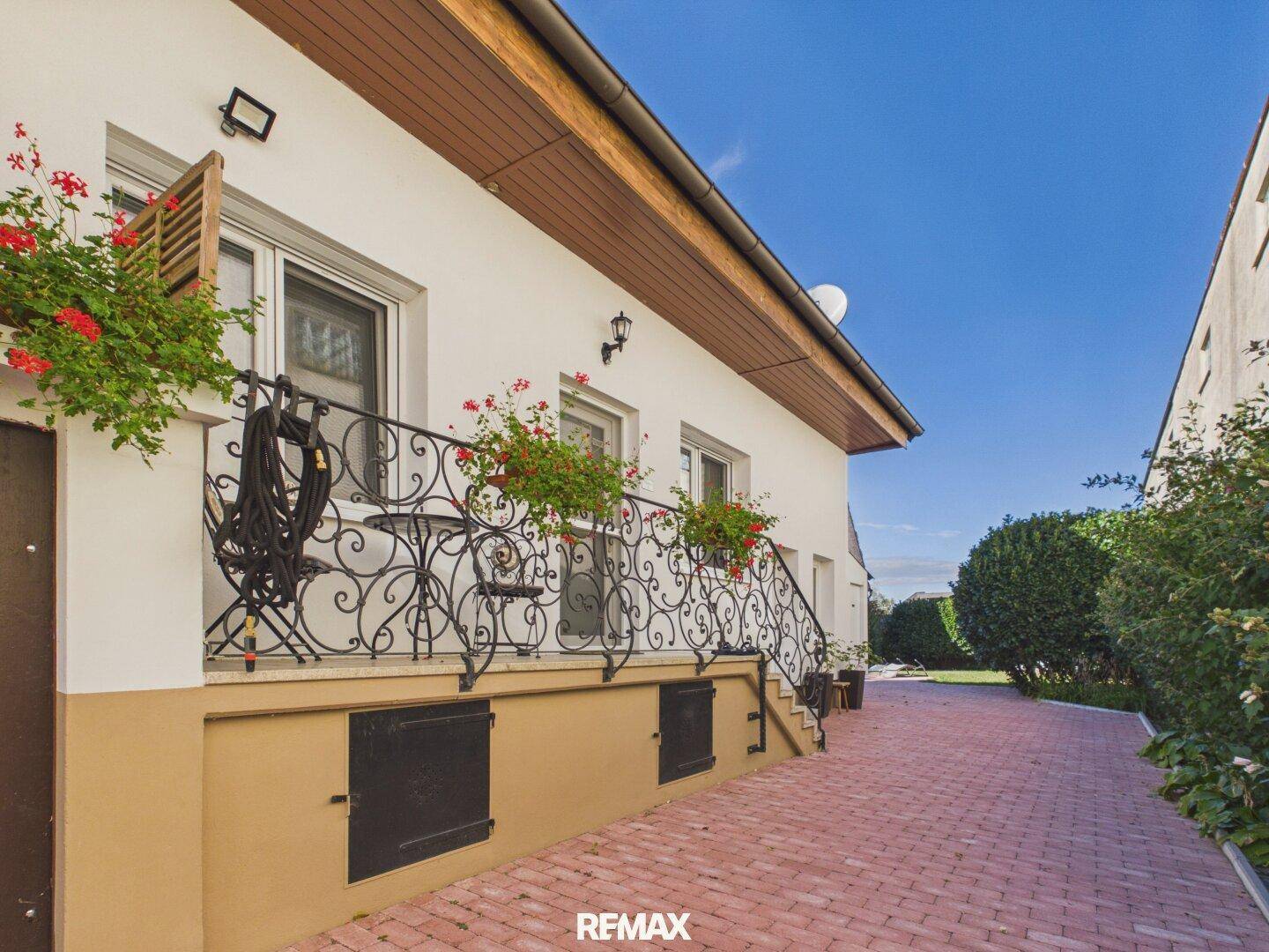 Kleiner Balkon mit schmiedeeisernem Geländer und Blumenkästen an der Hausfassade.