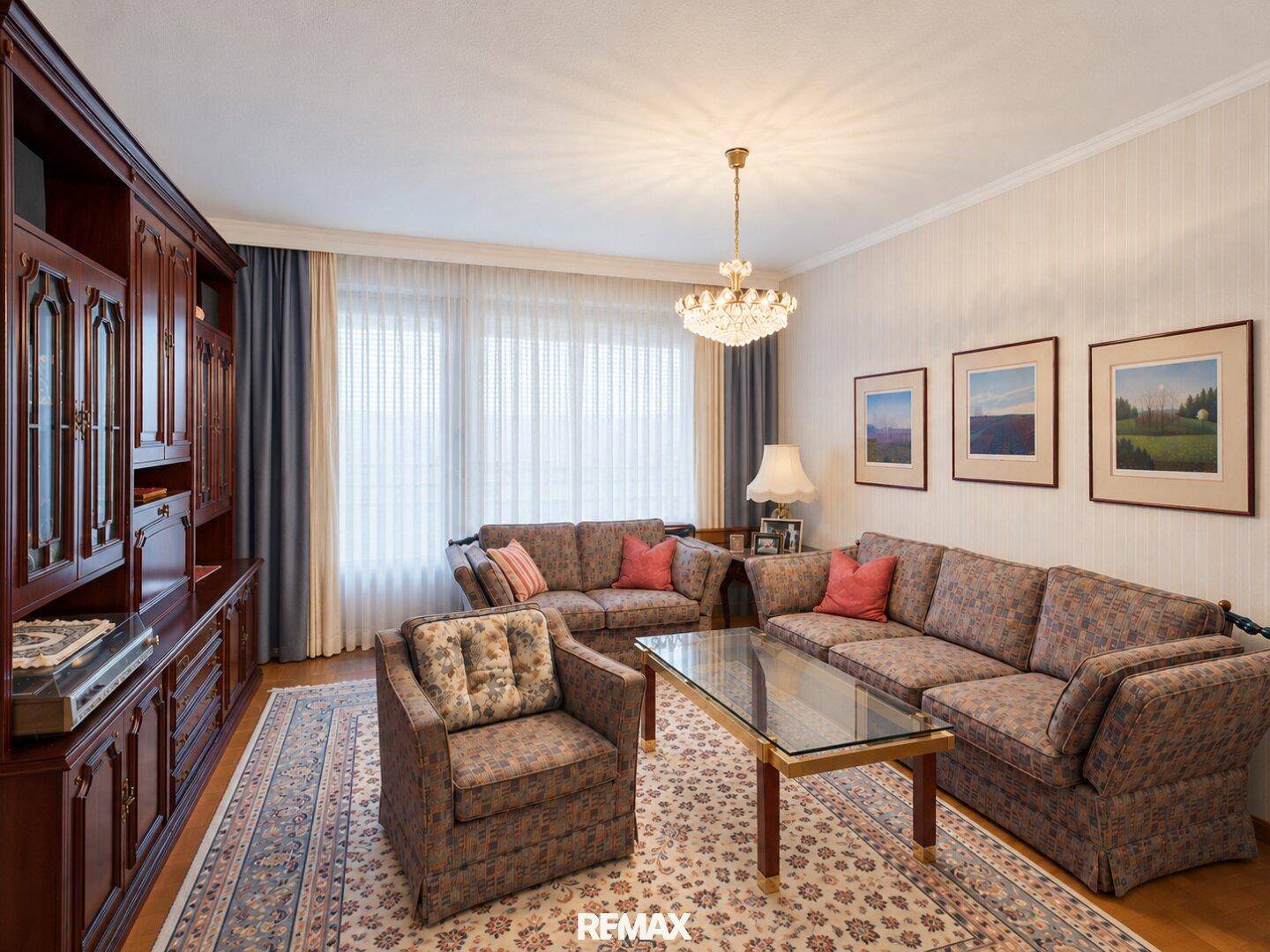 Gemütliches Wohnzimmer mit großem Sofa, Teppich und einem Kronleuchter, der für eine warme Beleuchtung sorgt.