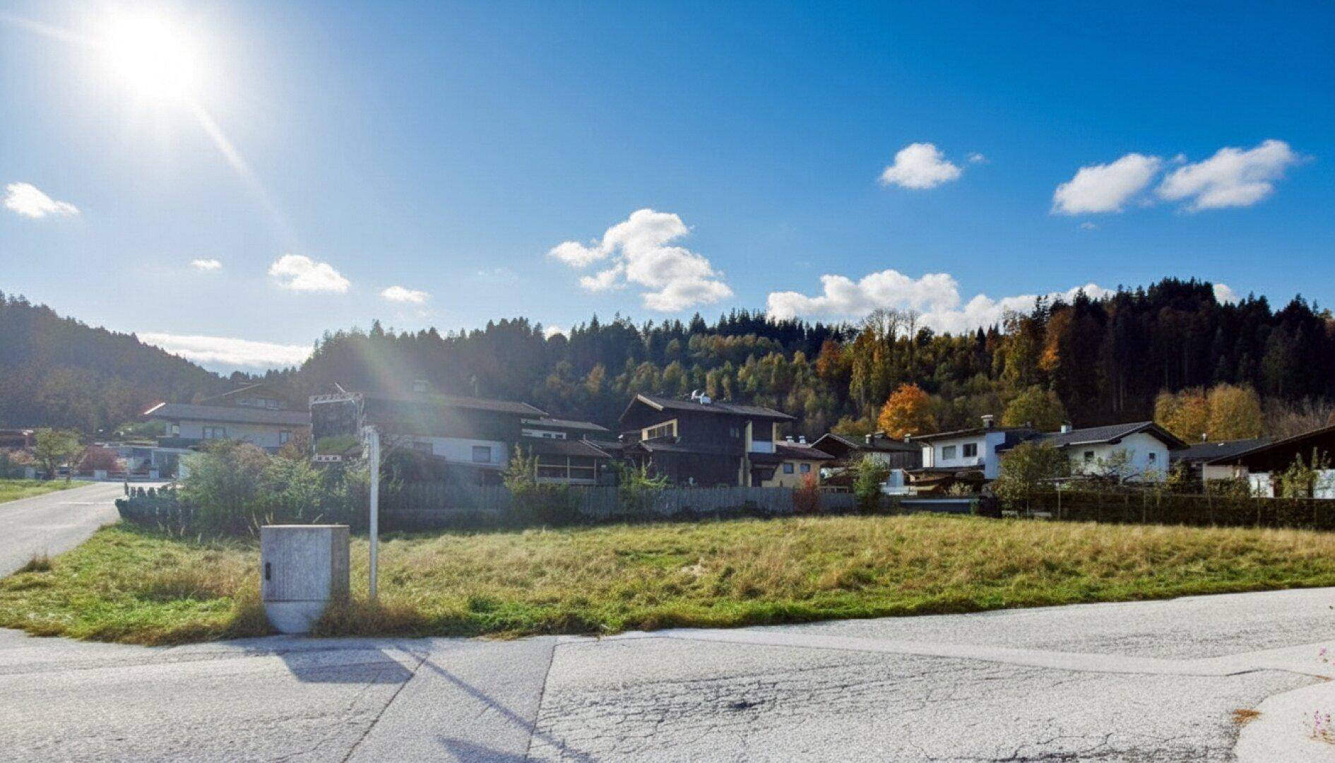 Sonniges Grundstück mit Blick auf die bewaldeten Hügel und umliegende Bebauung.