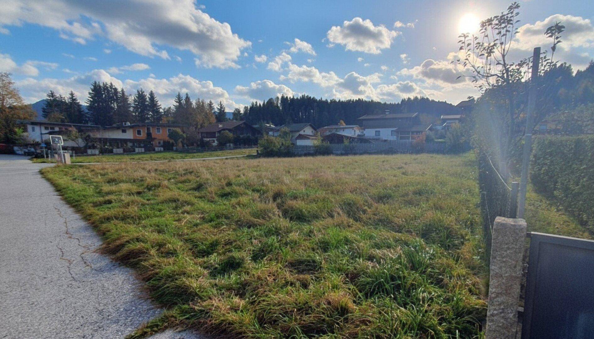 Sonniges, offenes Grundstück mit Blick auf die bewaldeten Hügel und die umliegende Bebauung.