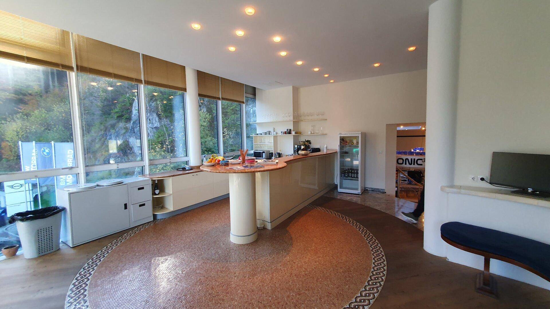 Moderner Loungebereich mit einer Bar, einzigartigem Mosaikfliesenboden und großen Fenstern mit Blick ins Grüne.