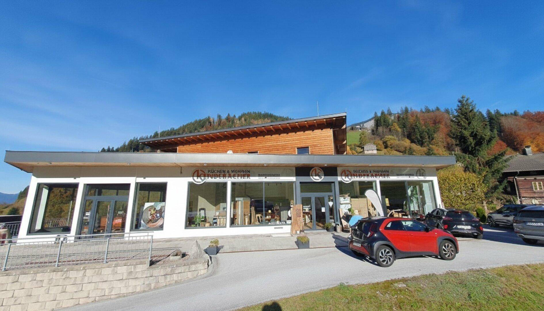 Vorderansicht des modernen Geschäftsgebäudes mit großen Schaufenstern und Eingangsbereich an einem sonnigen Tag.