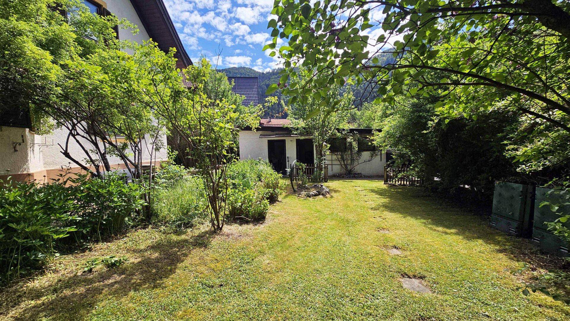 Garten mit Rasenfläche, einem kleinen Schuppen und dem seitlichen Blick auf das Wohnhaus.
