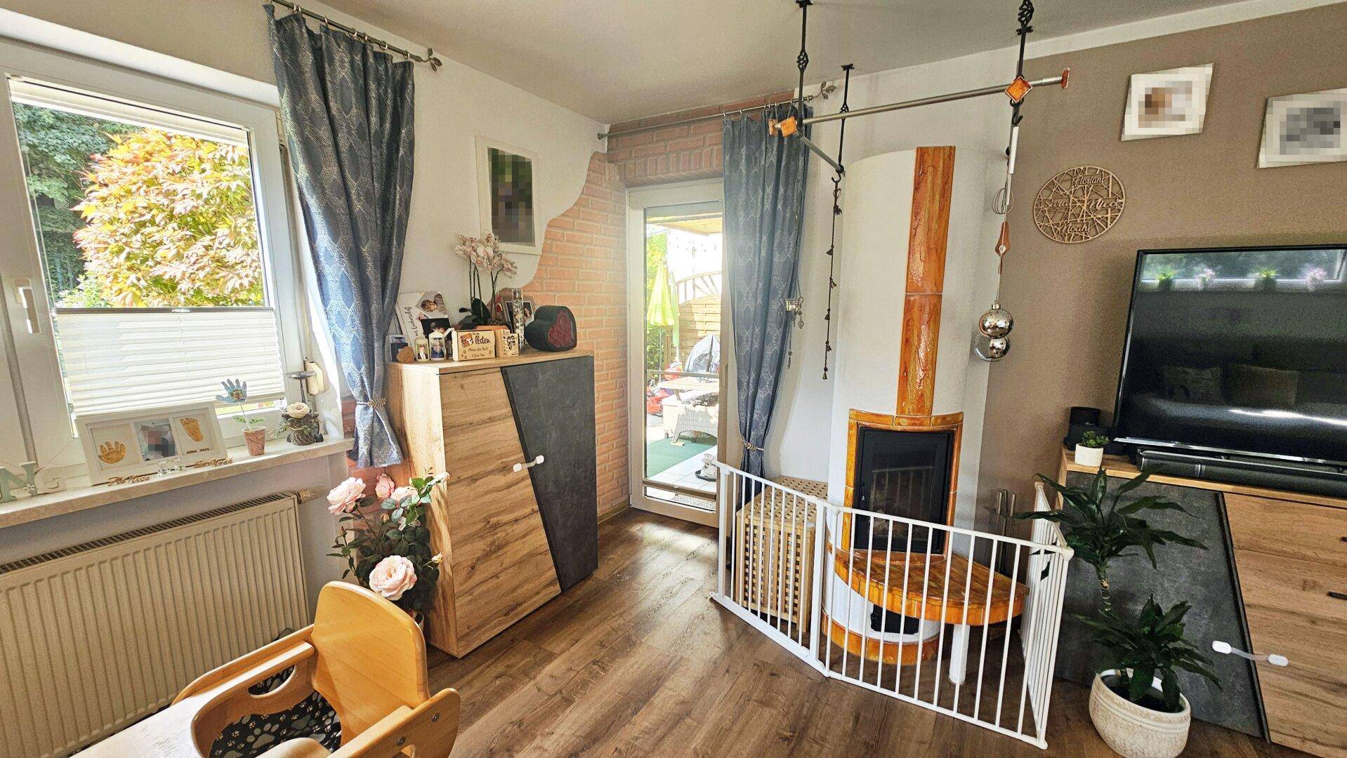 Helles Wohnzimmer mit modernem Kamin, Laminatboden und direktem Zugang zur möblierten Terrasse.