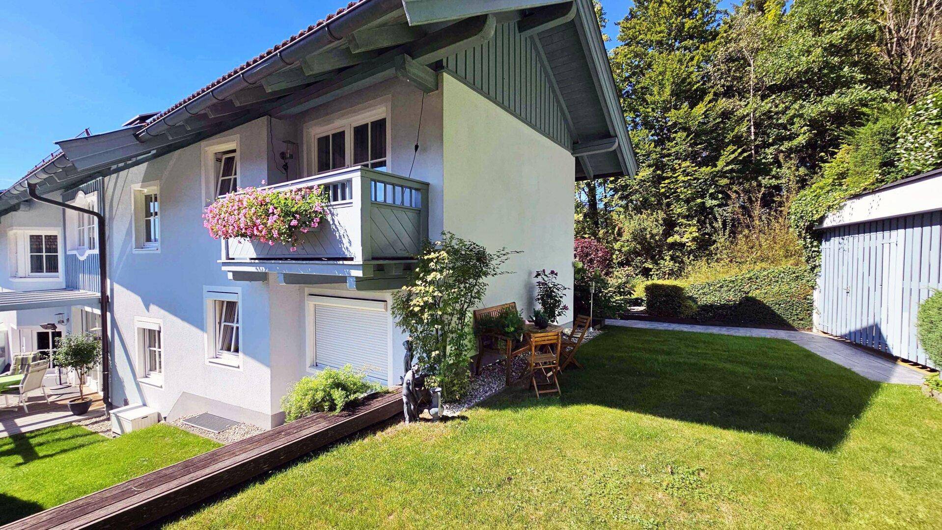 Attraktives Haus mit Balkon und gepflegtem Rasen, umgeben von Bäumen und Natur.