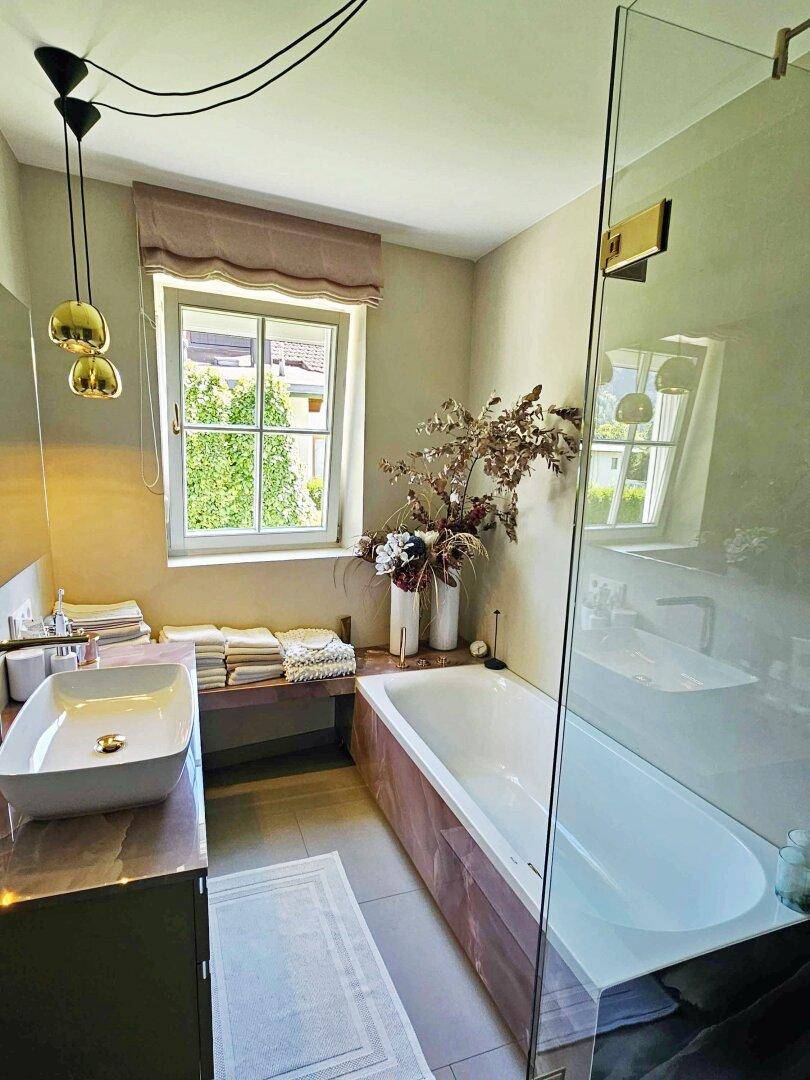 Modernes Badezimmer mit Badewanne, begehbarer Dusche und Fenster für Tageslicht.