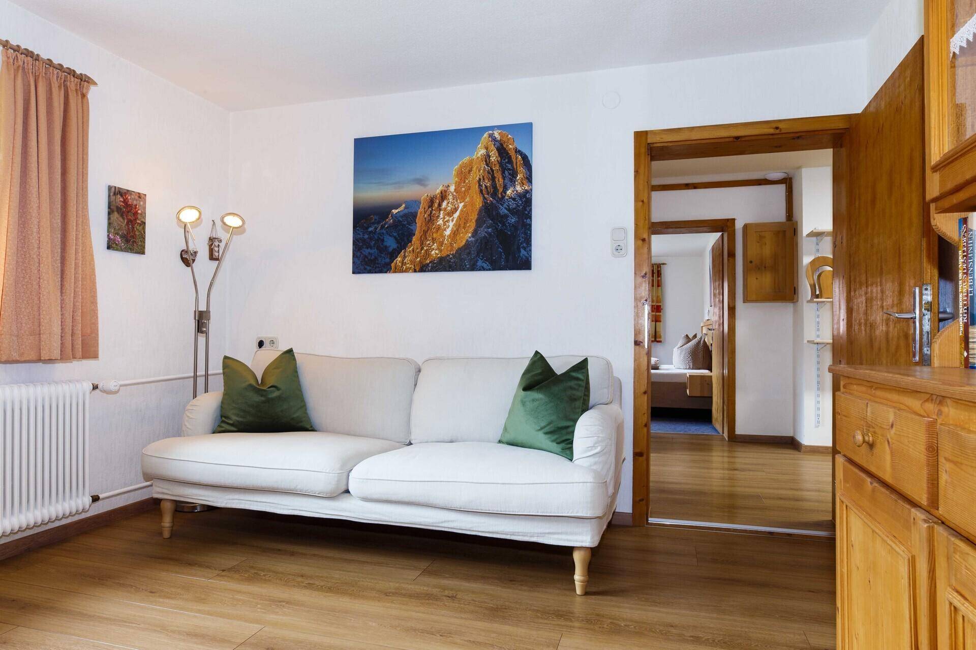 Helles Wohnzimmer mit weißem Sofa, Holzboden und Blick in den Flur.
