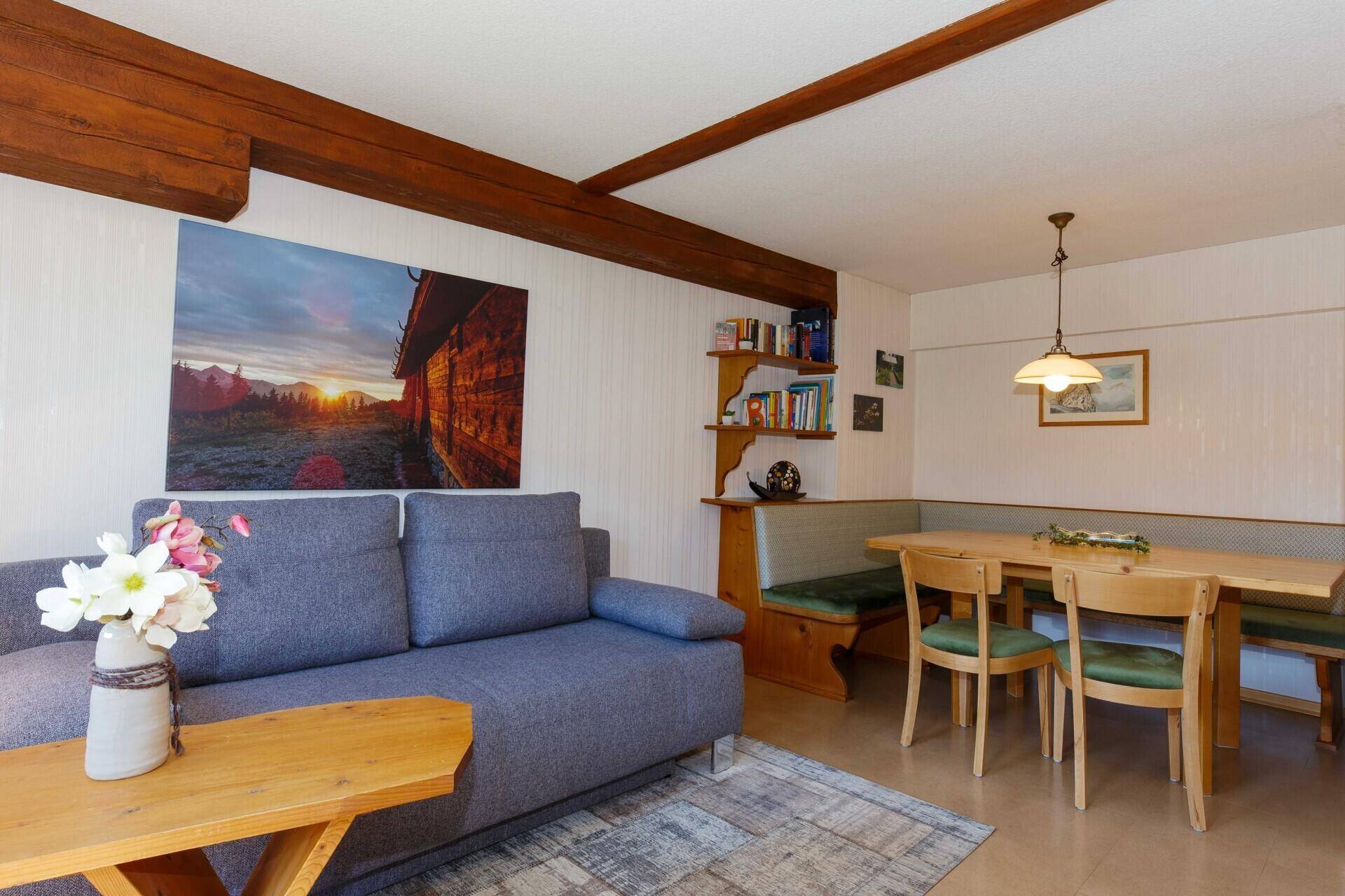 Gemütlicher Wohn-Essbereich mit Eckbank, Sofa und sichtbaren Holzbalken.
