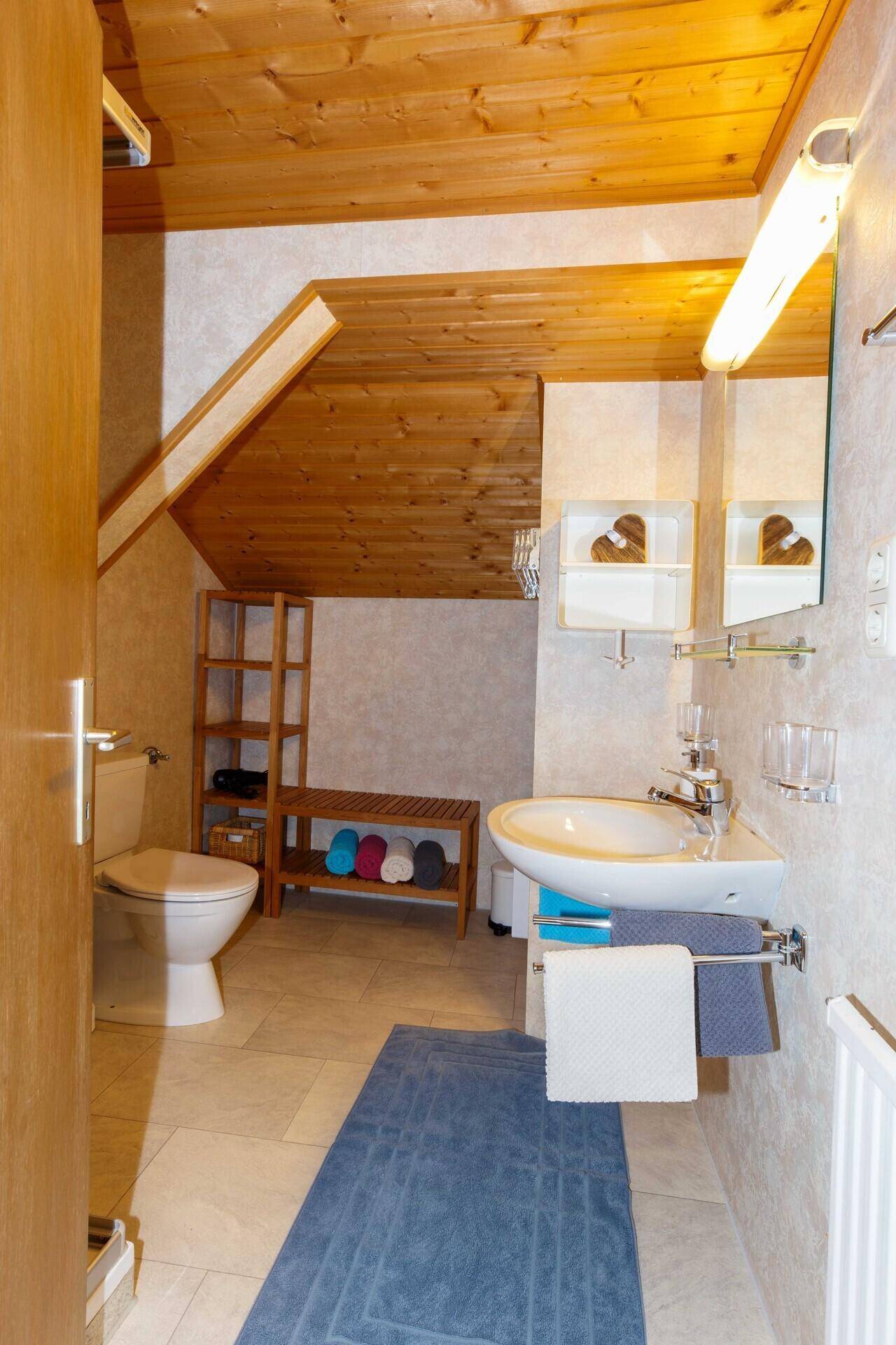 Helles Badezimmer mit WC, Waschbecken und praktischem Stauraum unter Dachschräge.
