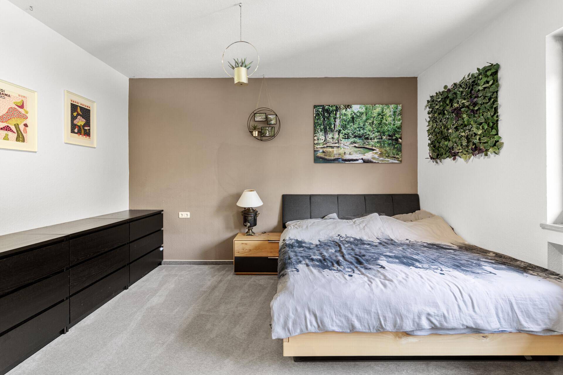 Schlafzimmer mit modernem Bett, langer Kommode und einer Akzentwand, die eine ruhige Atmosphäre schafft.