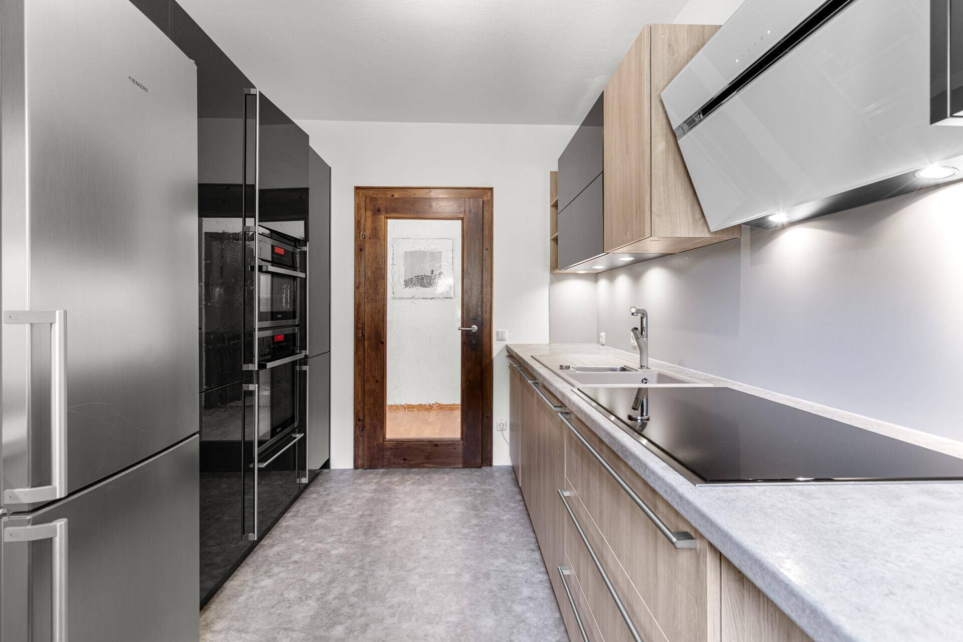 Moderne Küche mit hochwertigen Einbaugeräten, dunklen und hellen Holzfronten sowie Induktionskochfeld.
