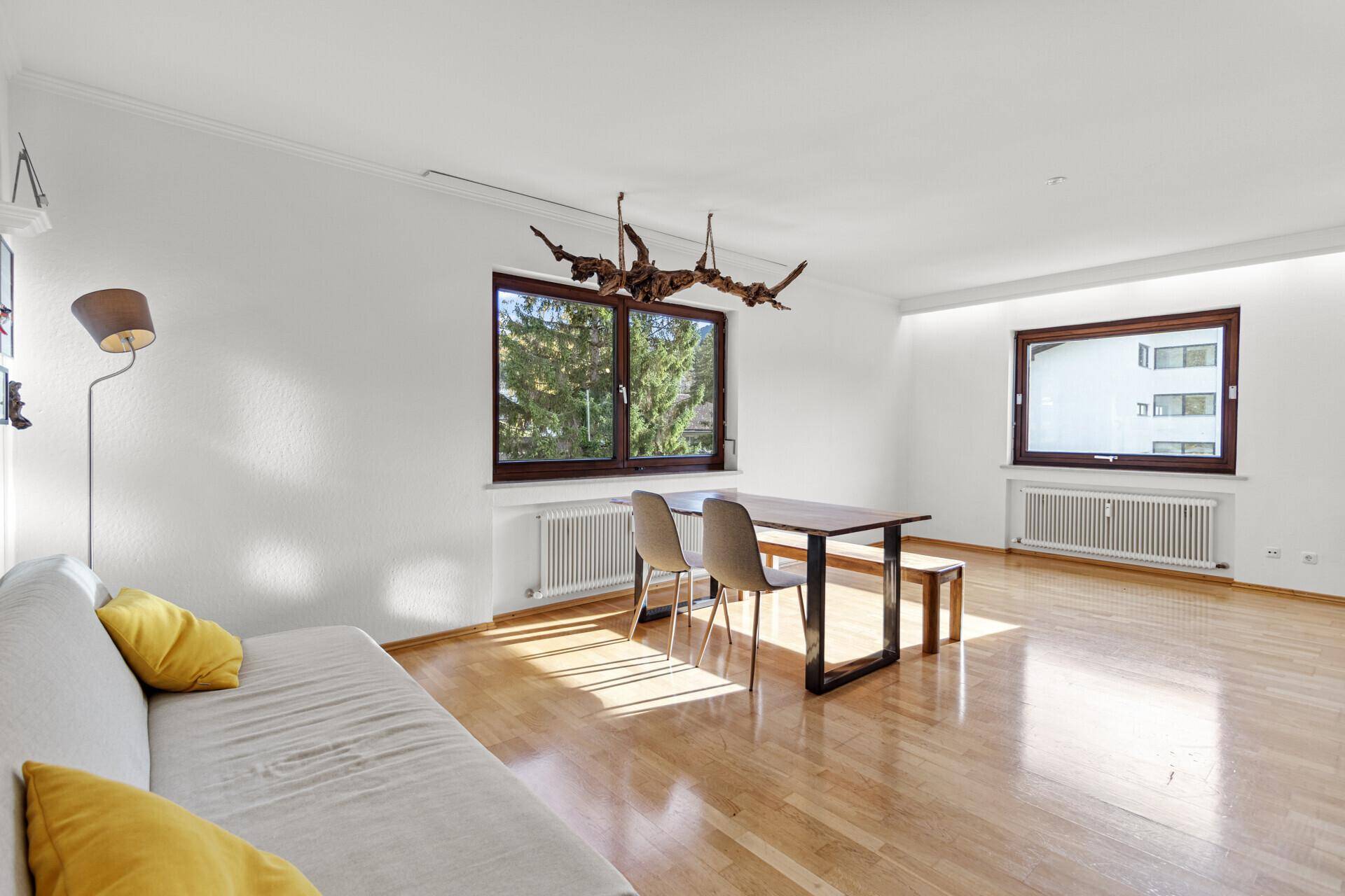 Geräumiger Wohn- und Essbereich mit Holzboden, Esstisch und Sofa, ideal für gesellige Stunden.