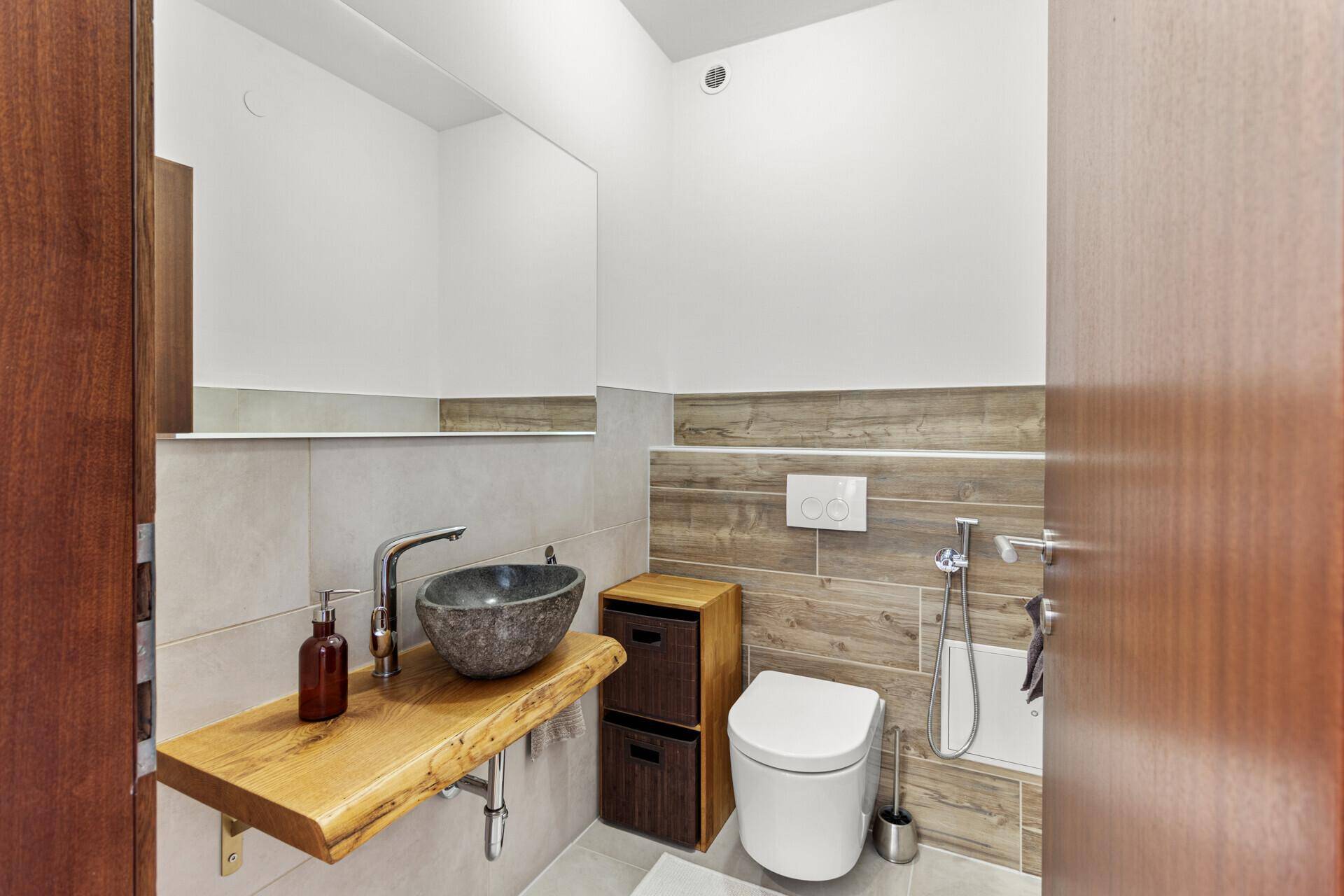 Modernes Gäste-WC mit stilvollem Holzwaschtisch, Steinsink und Wand-WC, in ansprechendem Design.