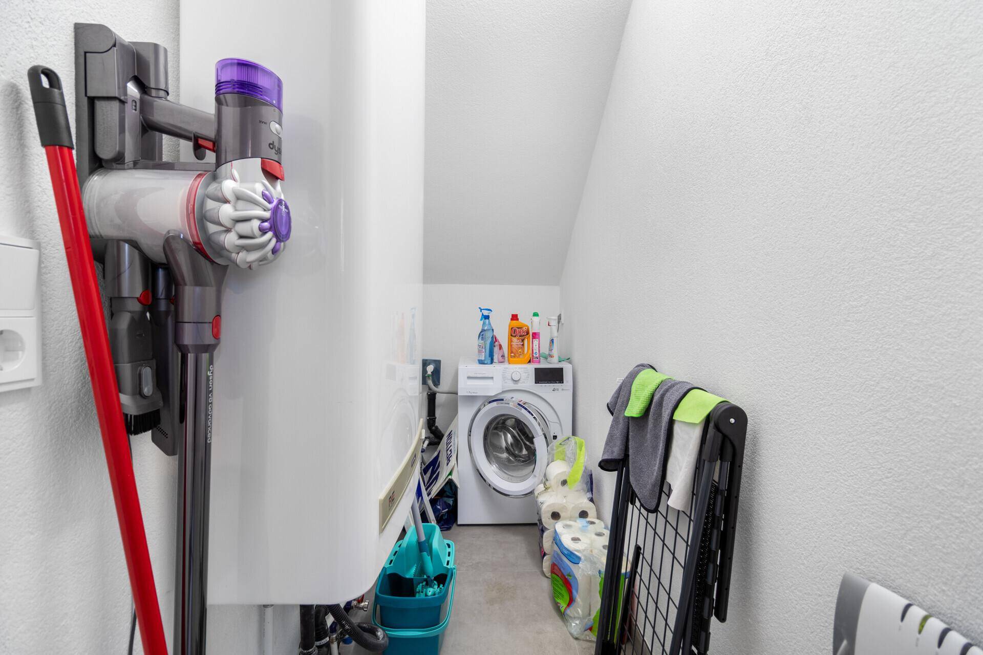 Praktischer Hauswirtschaftsraum mit Waschmaschine, Staubsauger und Reinigungsutensilien.