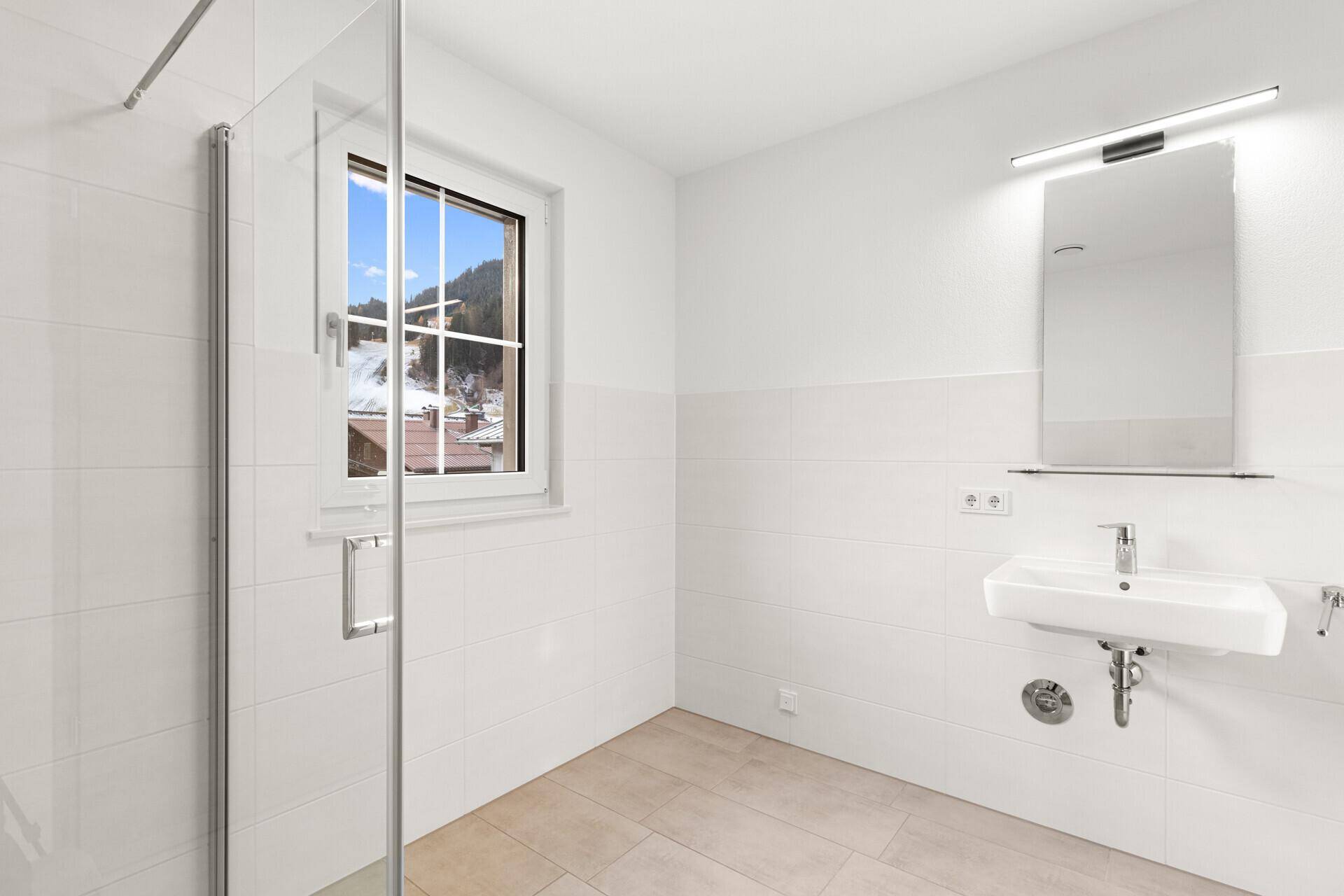 Modernes Badezimmer mit Dusche, Fenster und weißen Fliesen, bietet viel Tageslicht.