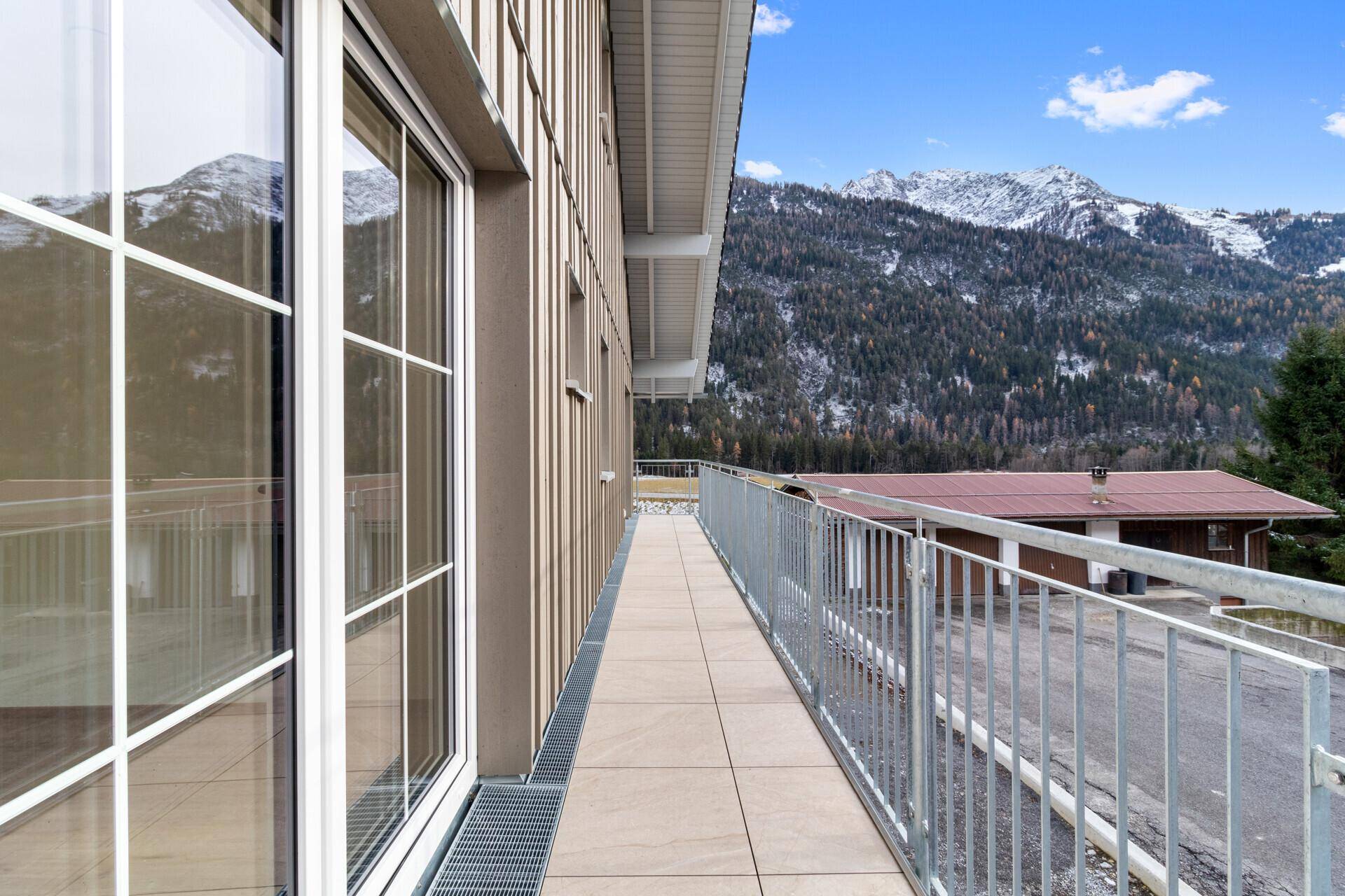 Langer Balkon mit Bergblick und Holzelementen an der Fassade, ideal zum Entspannen.