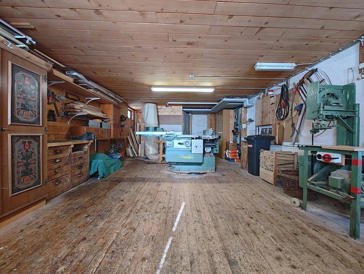 Geräumige Werkstatt mit Holzböden und -wänden, ausgestattet mit verschiedenen Holzbearbeitungsmaschinen.