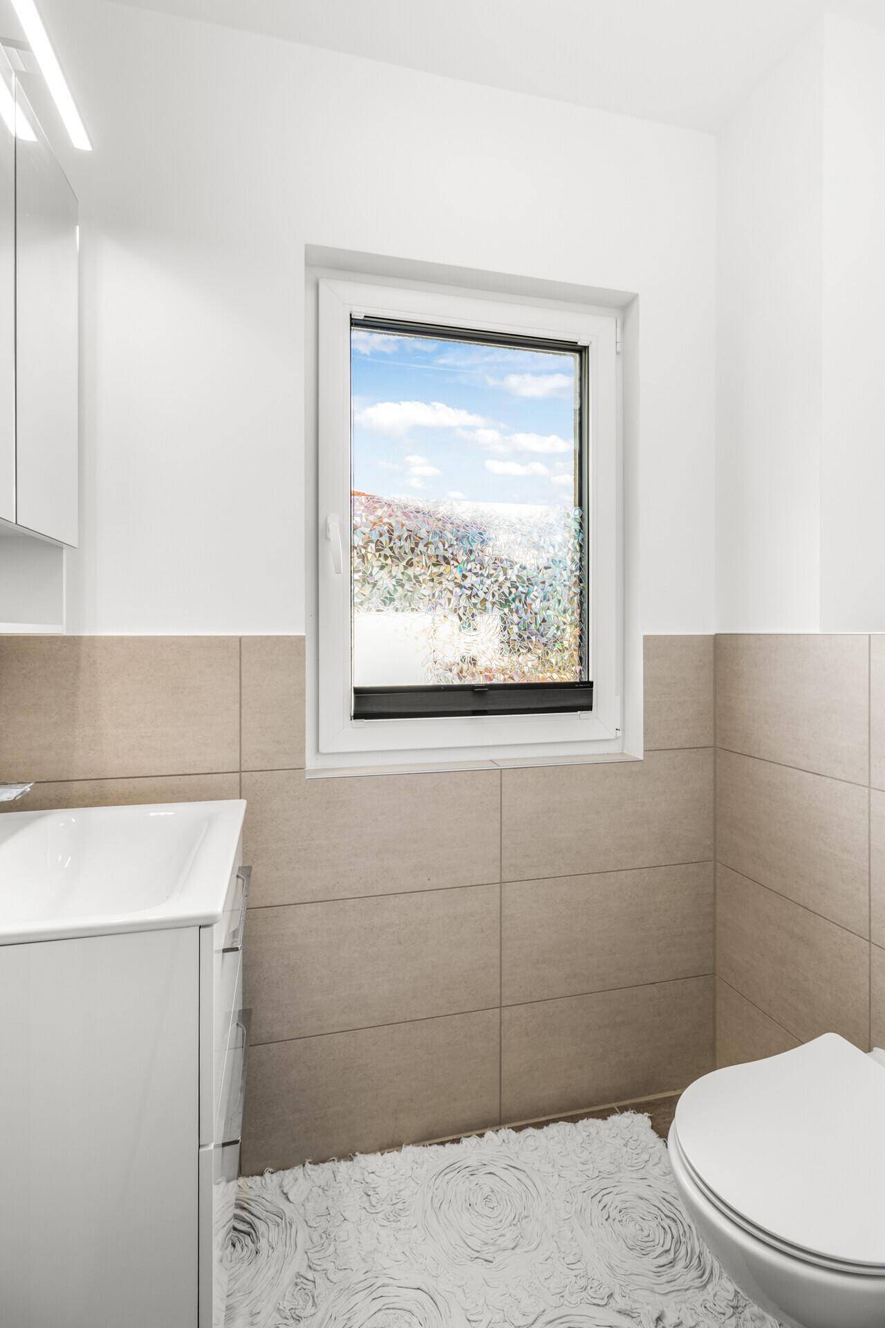 Kleines Badezimmer mit WC, Waschtisch und Fenster.
