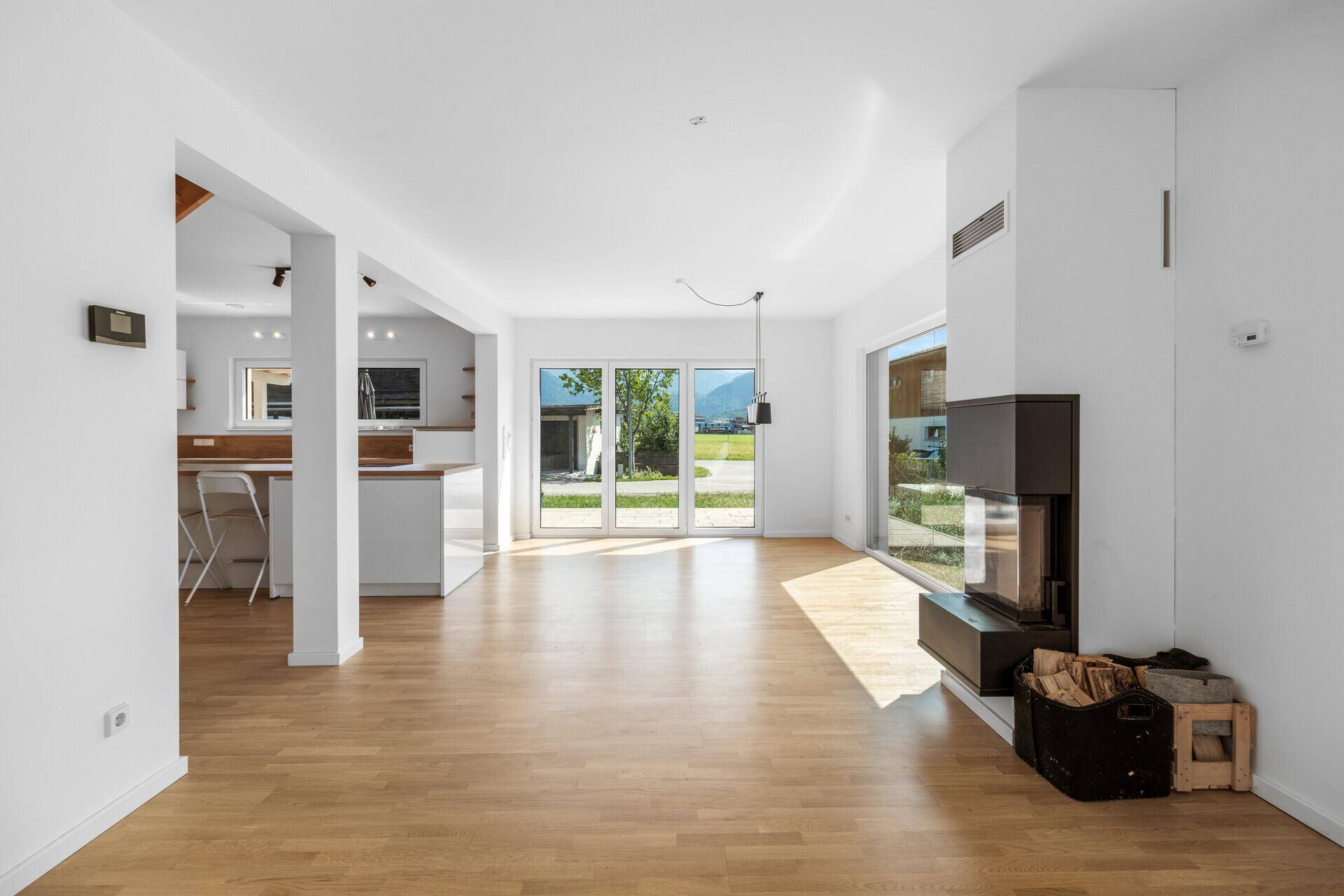 Geräumiges Wohnzimmer mit Kaminofen, Holzboden und großen Fenstern zum Garten.