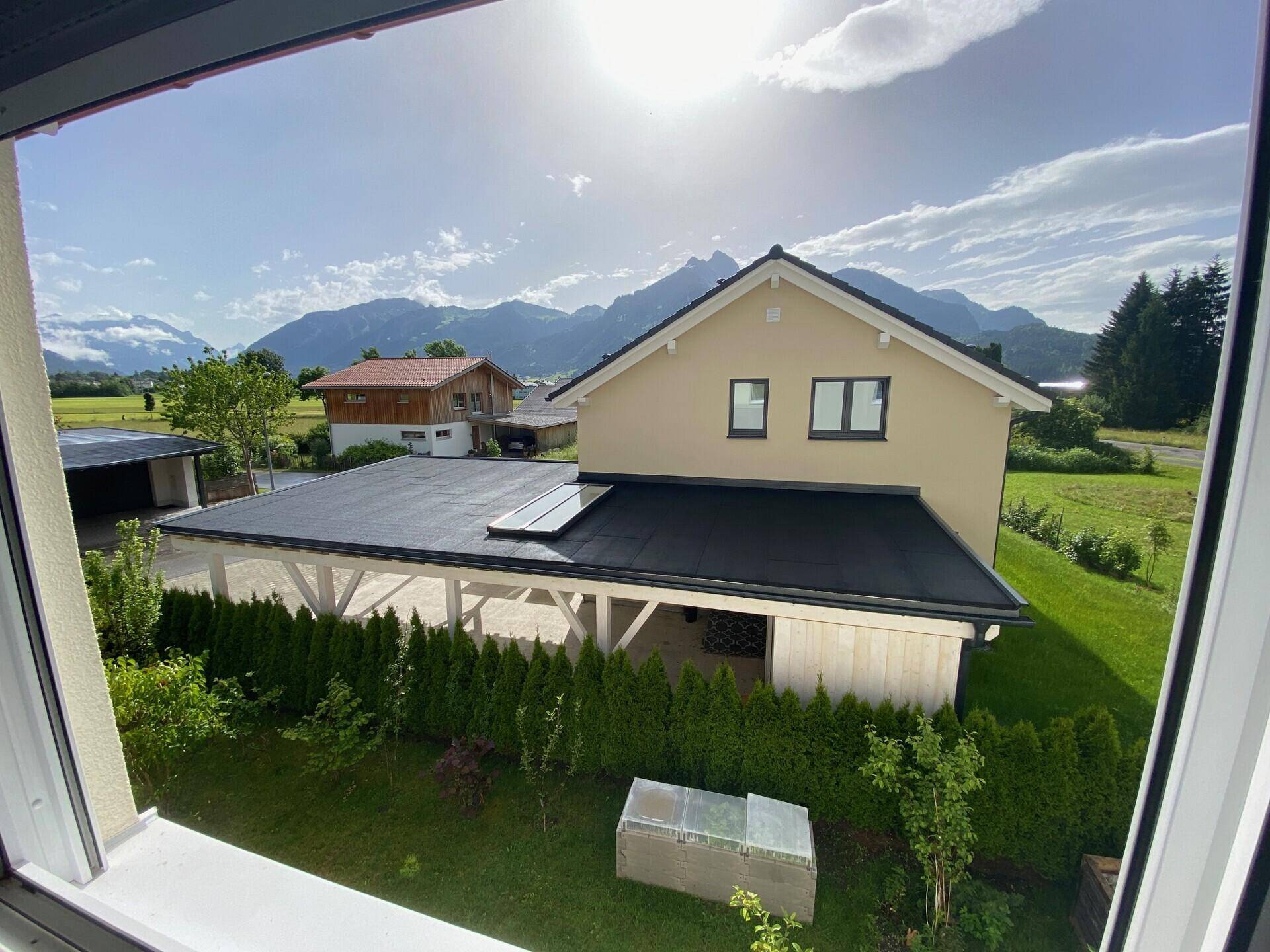 Ansicht des Hauses von oben mit Carport, Garten und Bergblick.