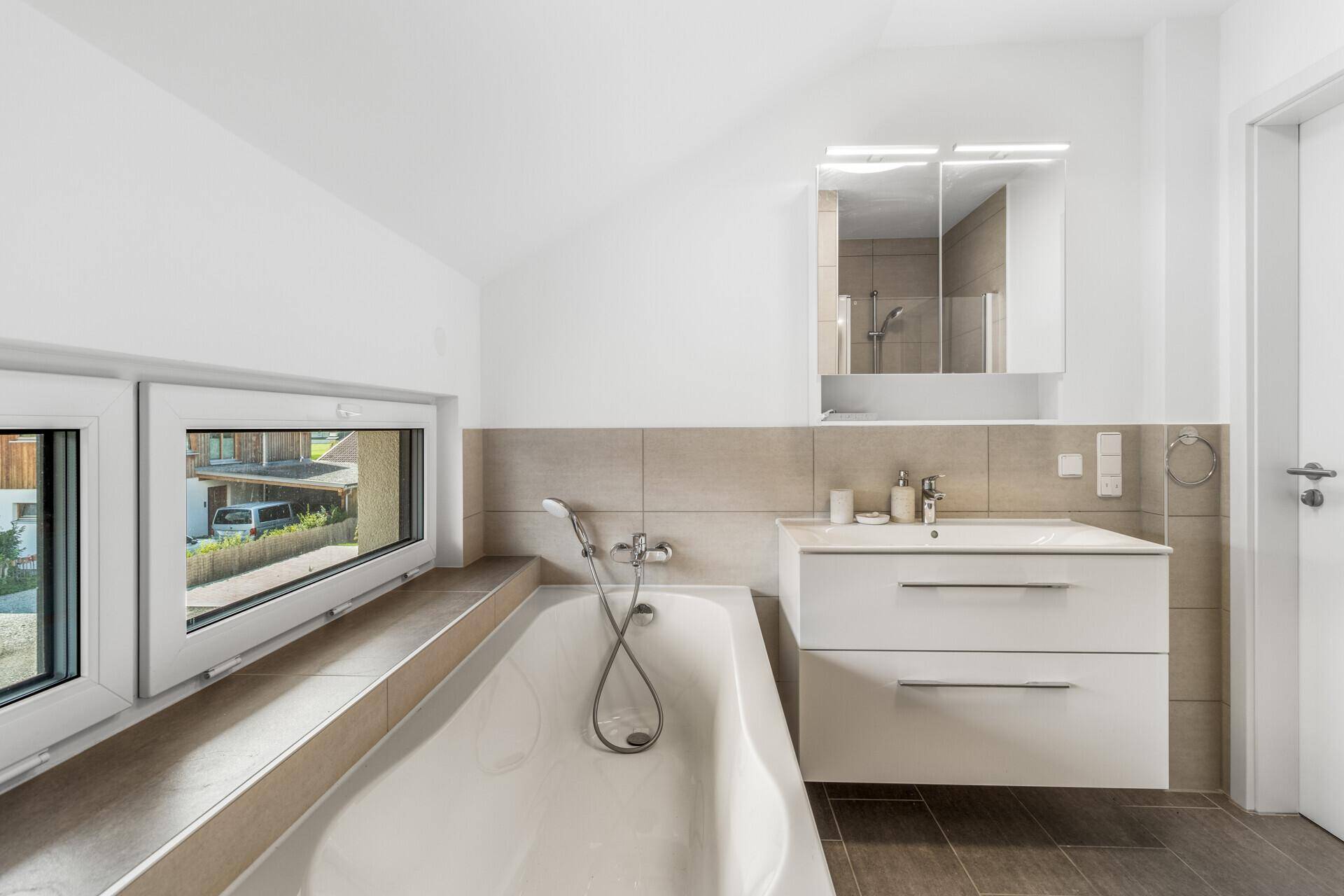 Helles Badezimmer im Dachgeschoss mit Badewanne, Waschtisch und Spiegelschrank.