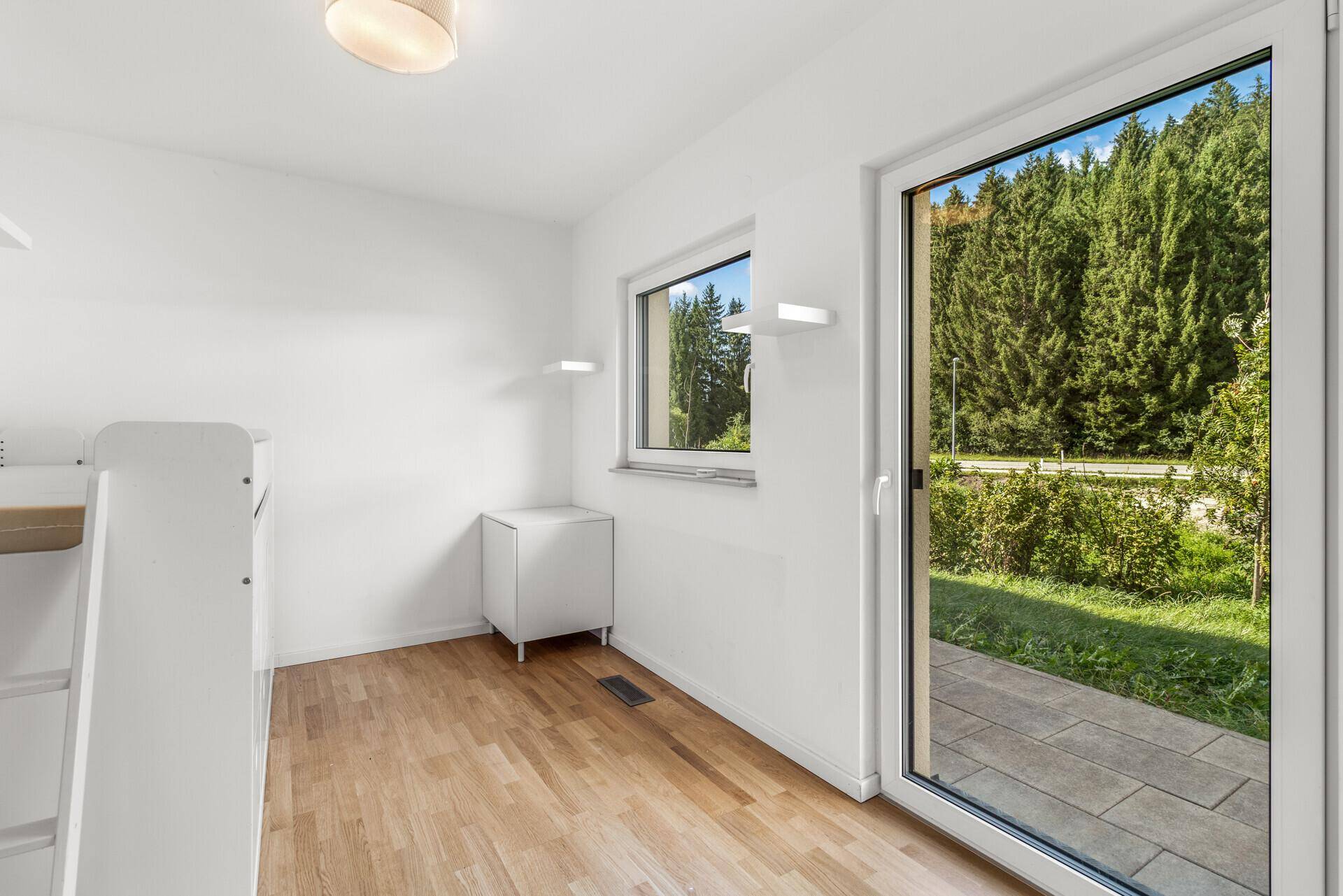 Helles Schlafzimmer mit Holzboden und direktem Zugang zum Garten oder zur Terrasse.