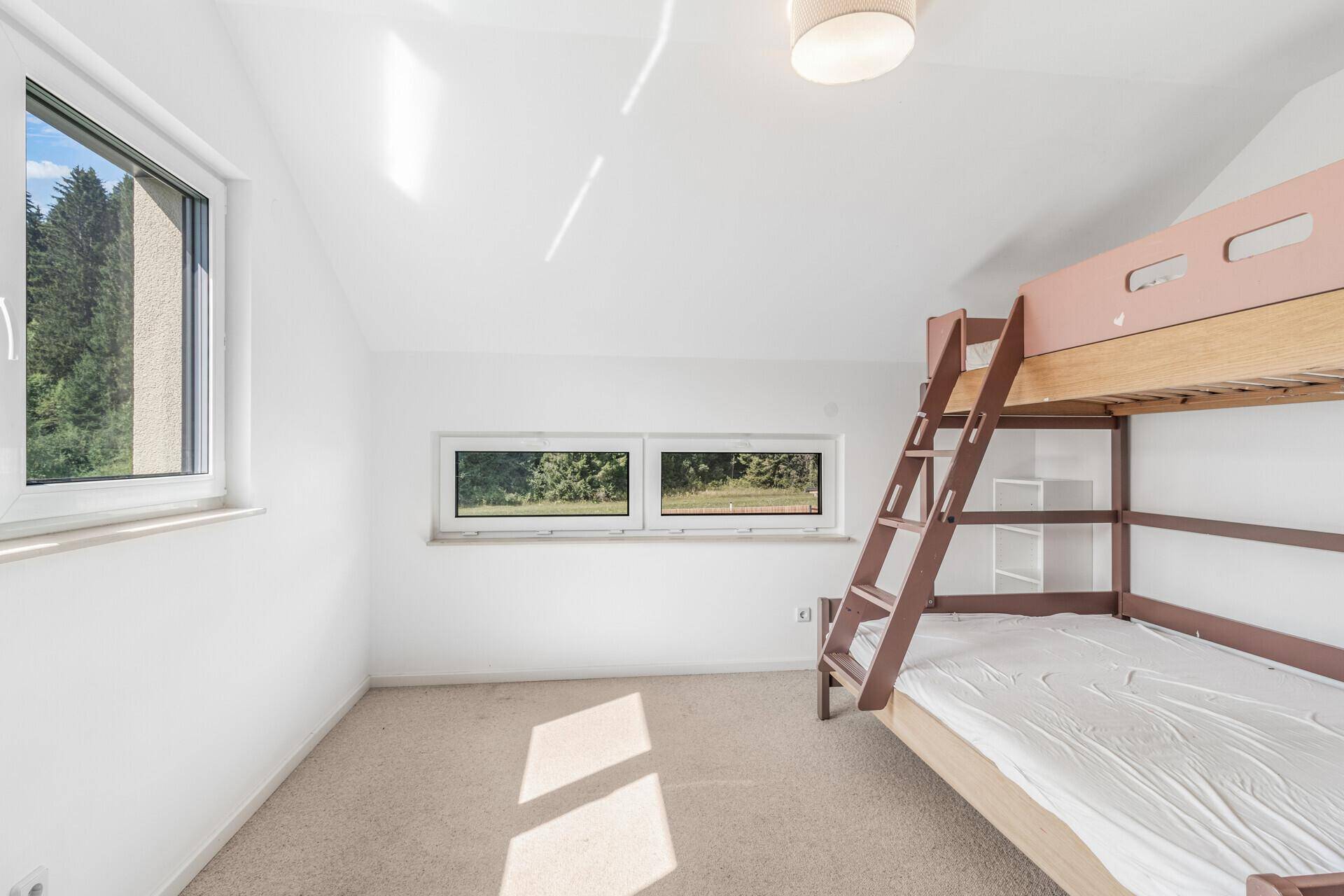 Kinderzimmer im Dachgeschoss mit Etagenbett, Teppichboden und Blick ins Grüne.