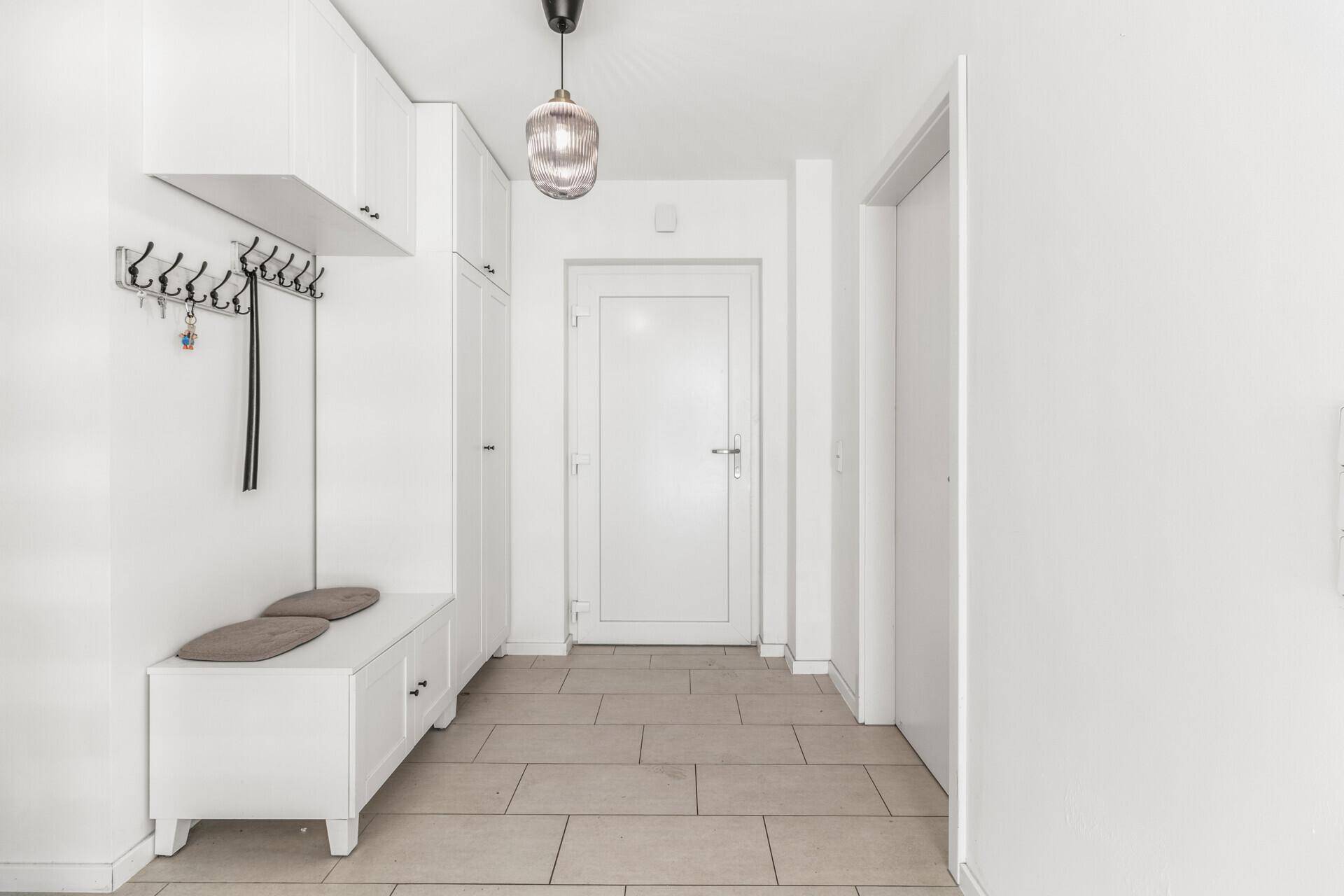 Eingangsbereich mit Fliesenboden, Garderobe und weißer Tür.
