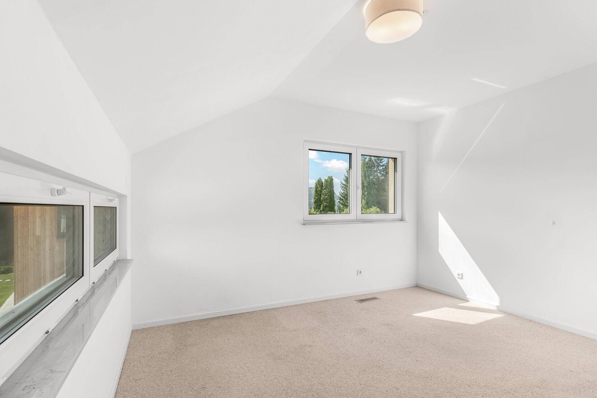 Helles Schlafzimmer im Dachgeschoss mit Teppichboden und viel Tageslicht.