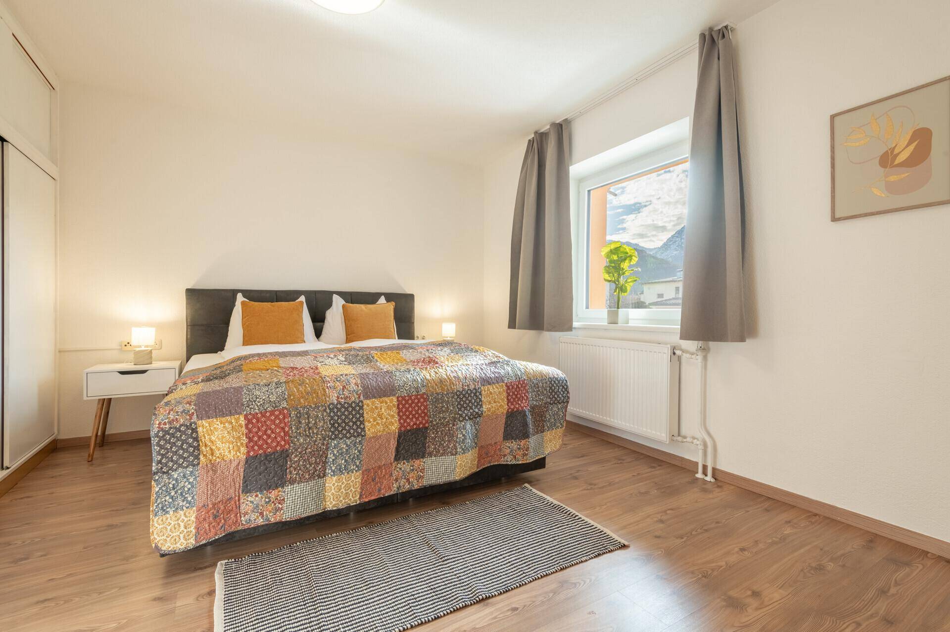 Schlafzimmer mit Doppelbett, Holzboden und Fenster mit Bergblick.