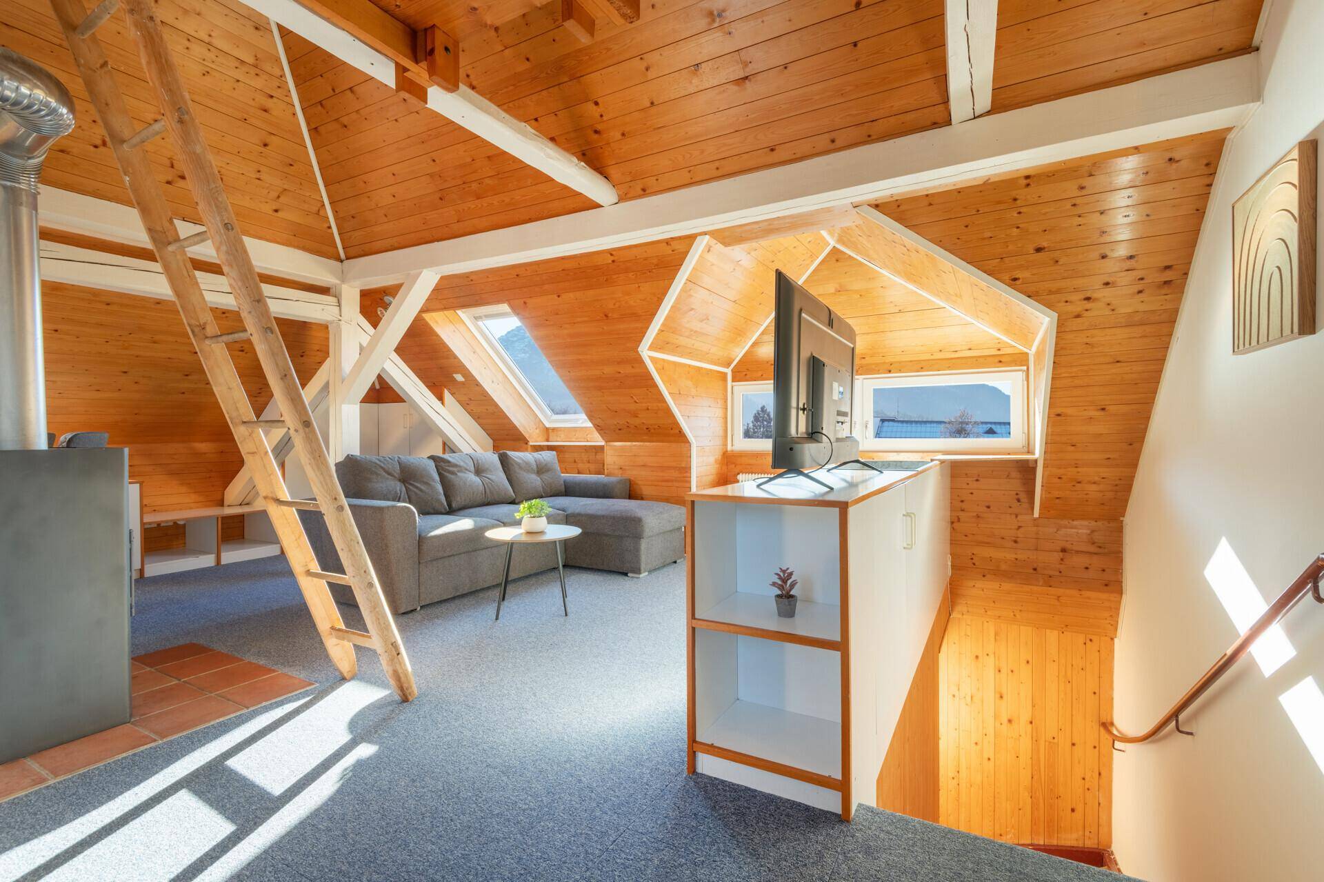 Geräumiger Dachgeschoss-Wohnbereich mit Holzwänden, Dachfenstern und Treppenaufgang.