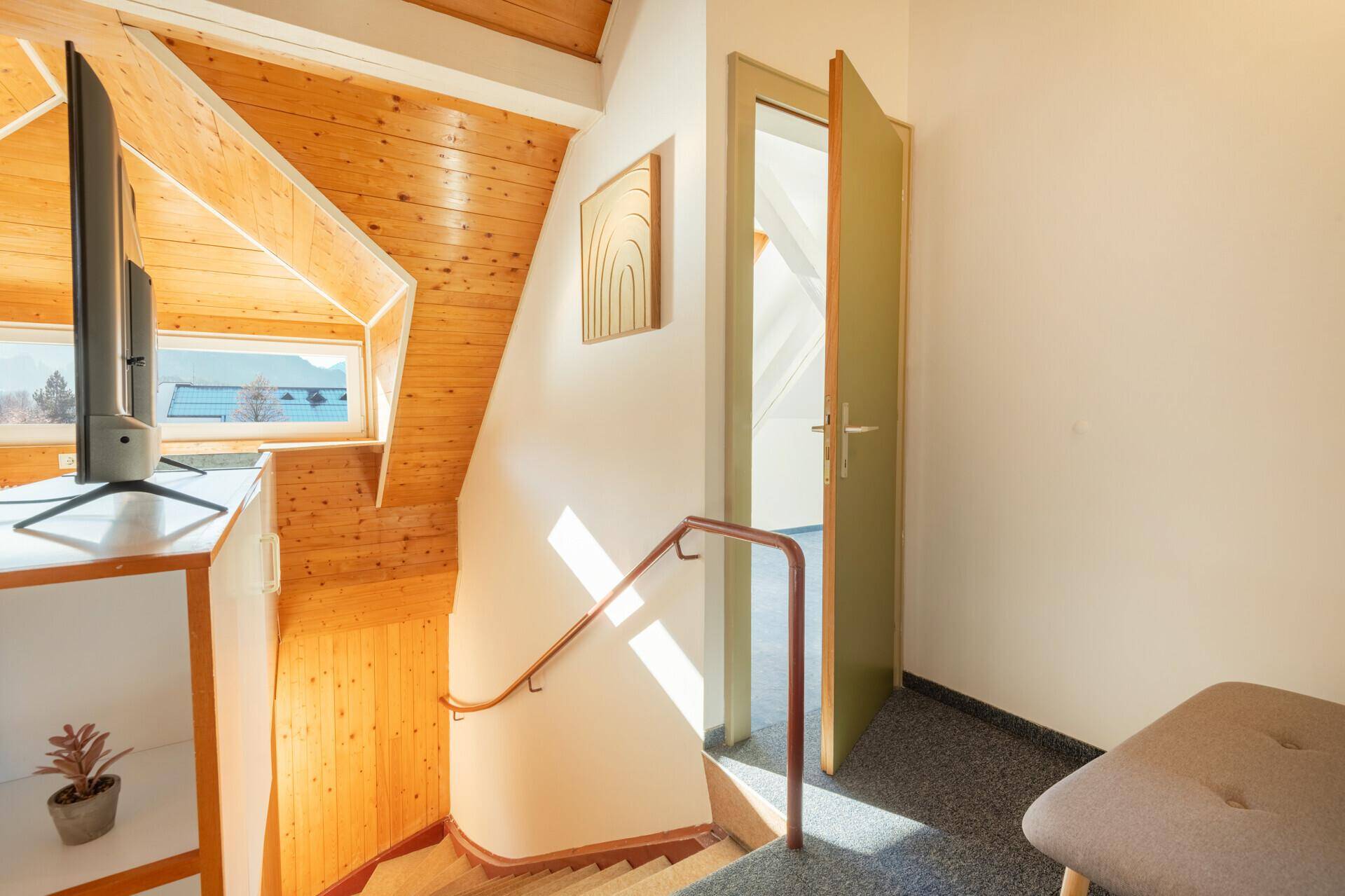 Treppenaufgang im Dachgeschoss mit Holzwänden und Blick auf den Wohnbereich.