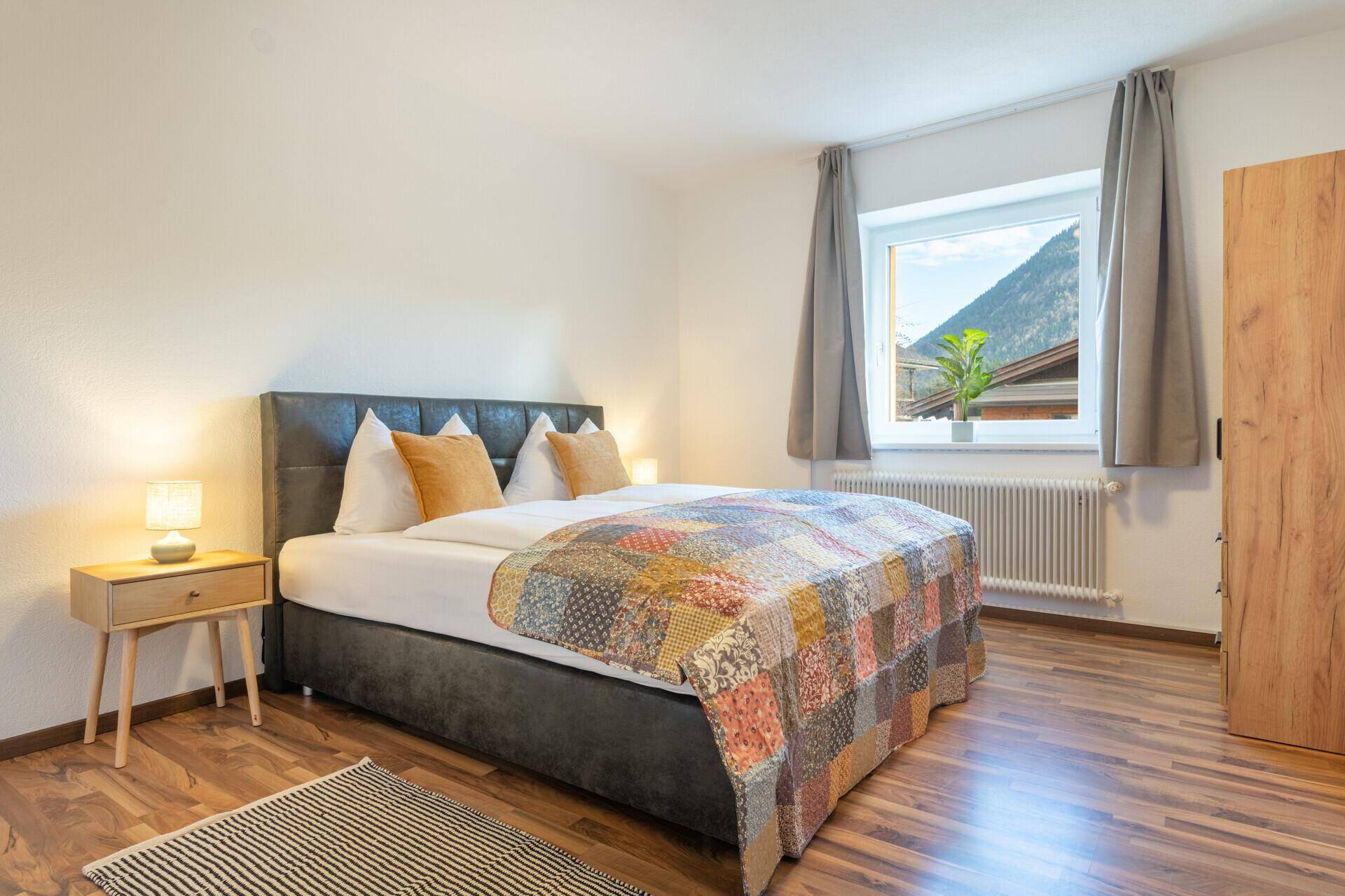 Helles Schlafzimmer mit Doppelbett, Holzboden und Kleiderschrank.