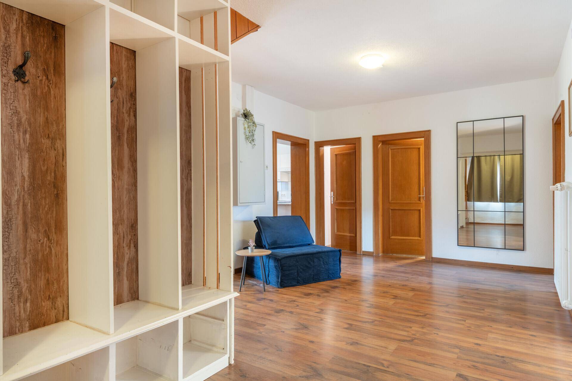 Geräumiger Flur mit Holzboden, Garderobe und großem Spiegel.