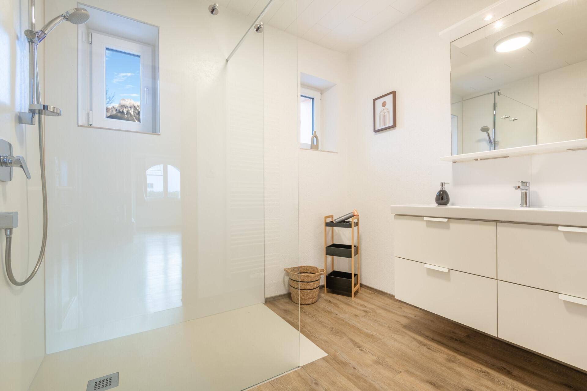 Modernes Badezimmer mit ebenerdiger Dusche, Doppelwaschbecken und Fenster.