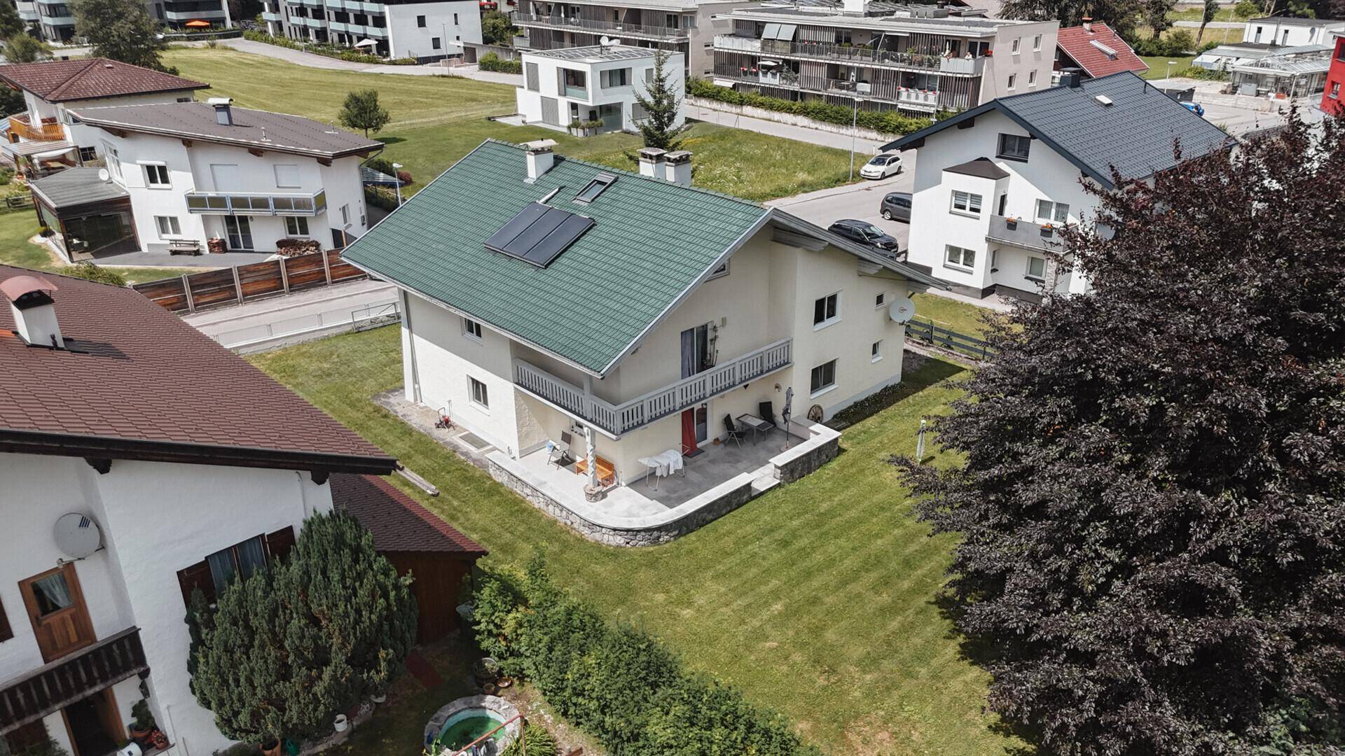 Luftaufnahme des Hauses mit großem Garten, Terrasse und Solaranlage auf dem grünen Dach.