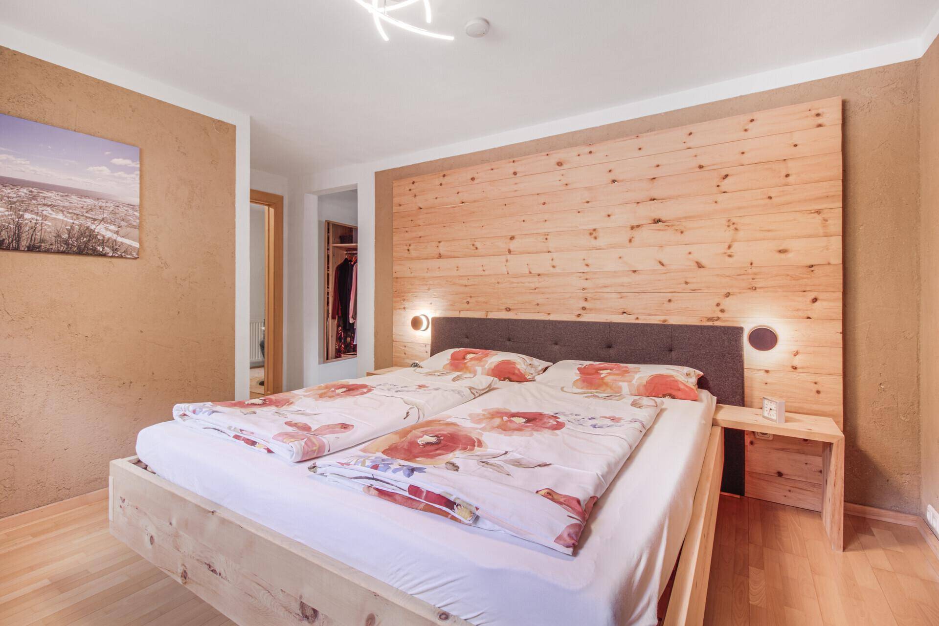 Helles Schlafzimmer mit Holzbett und rustikaler Holzvertäfelung, bietet eine warme Atmosphäre.