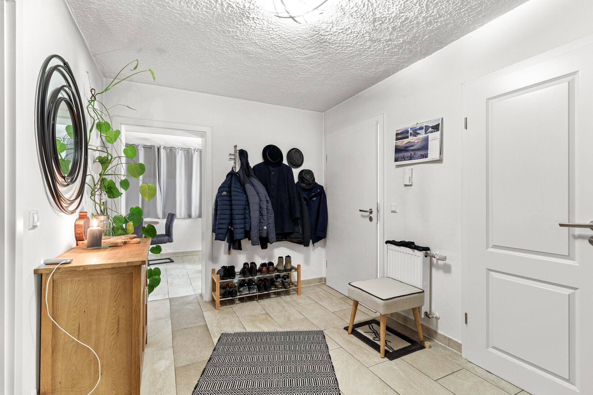 Heller Eingangsbereich mit Garderobe, Schuhregal und Fliesenboden.