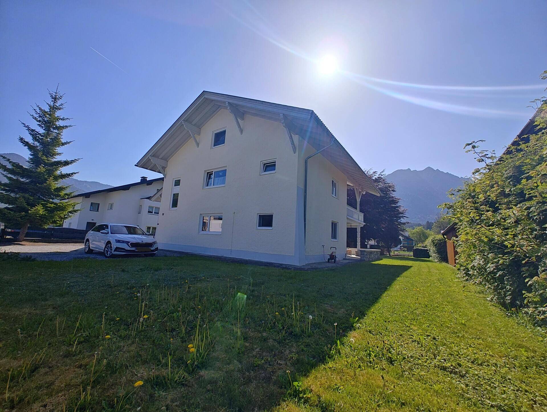 Seitenansicht des Hauses mit weitläufiger Rasenfläche und sonnigem Grundstück.