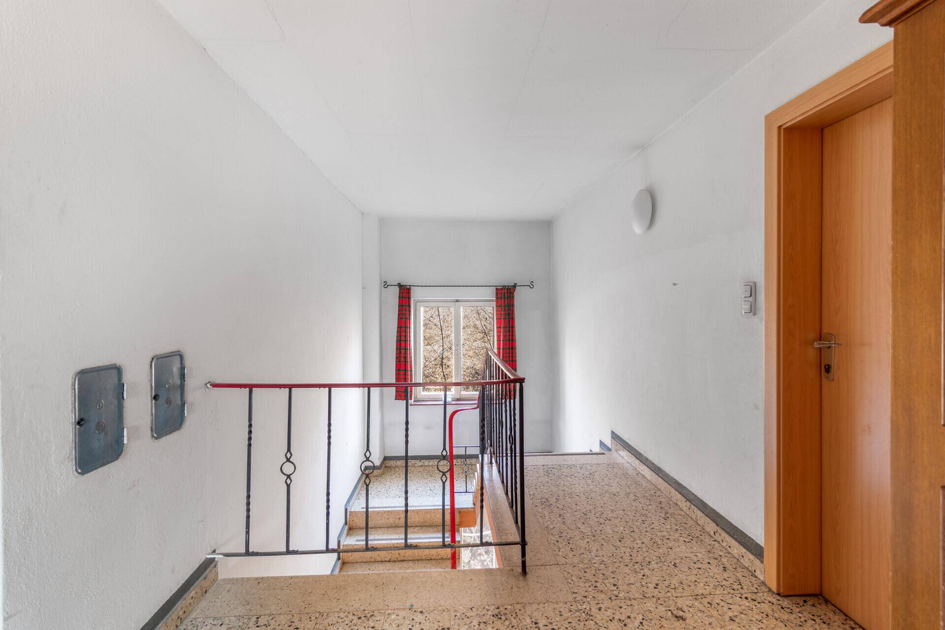 Helles Treppenhaus mit Terrazzoboden und Zugang zu den oberen Etagen.