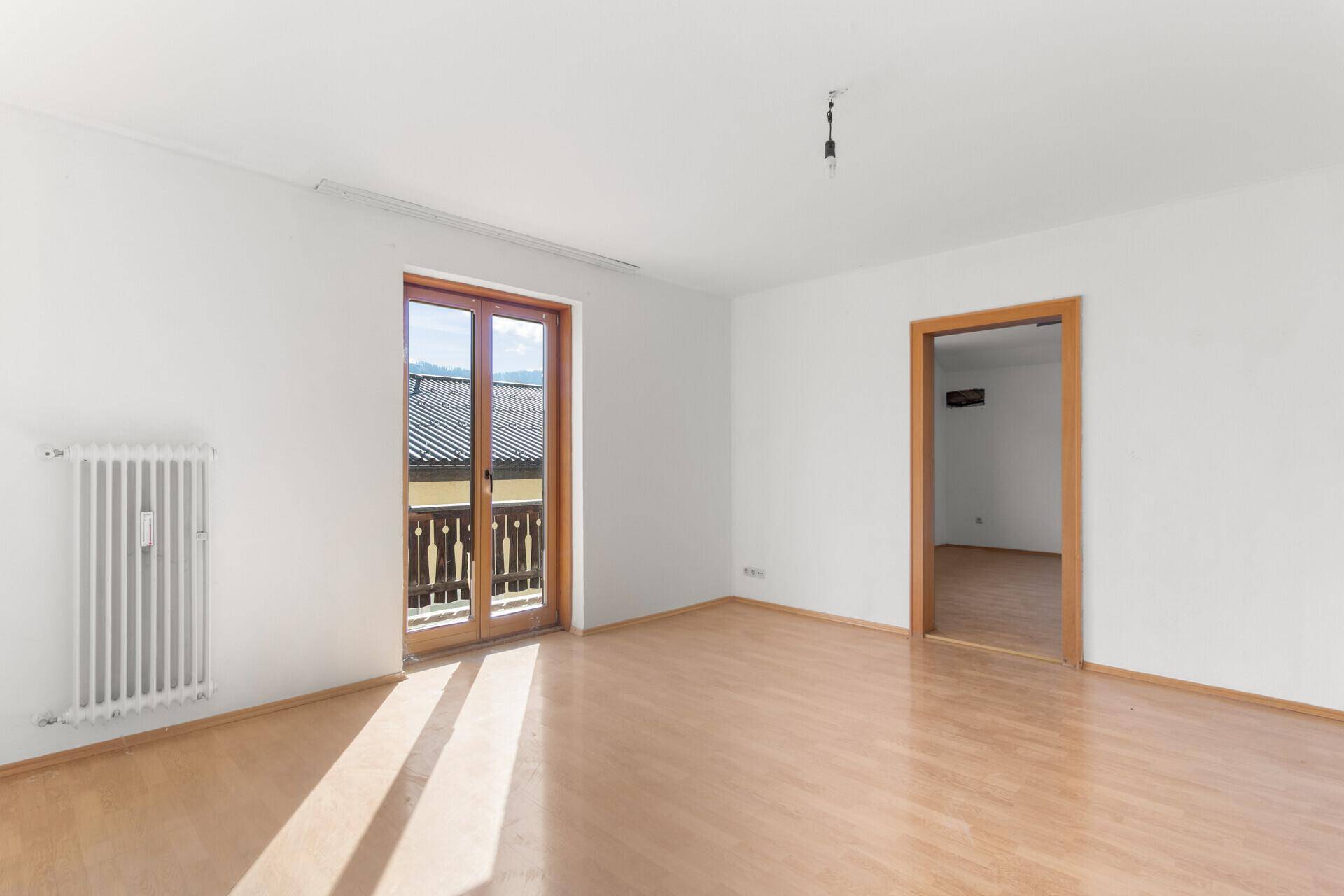 Heller Wohnraum mit Laminatboden und direktem Zugang zu einem Balkon.