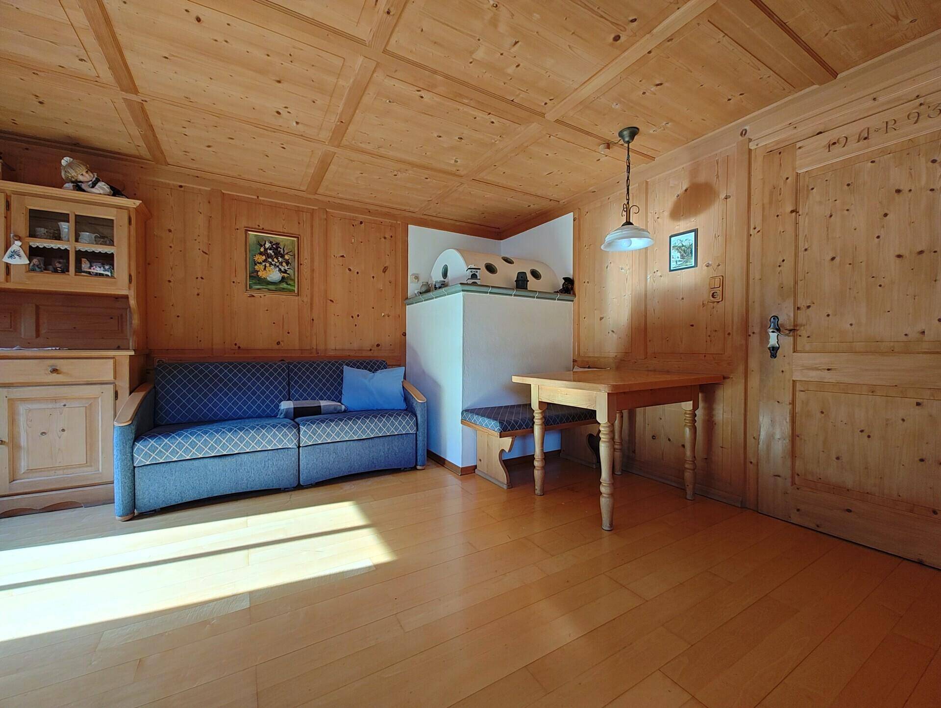 Traditionelles Wohnzimmer im alpinen Stil mit Kachelofen und Holzvertäfelung.