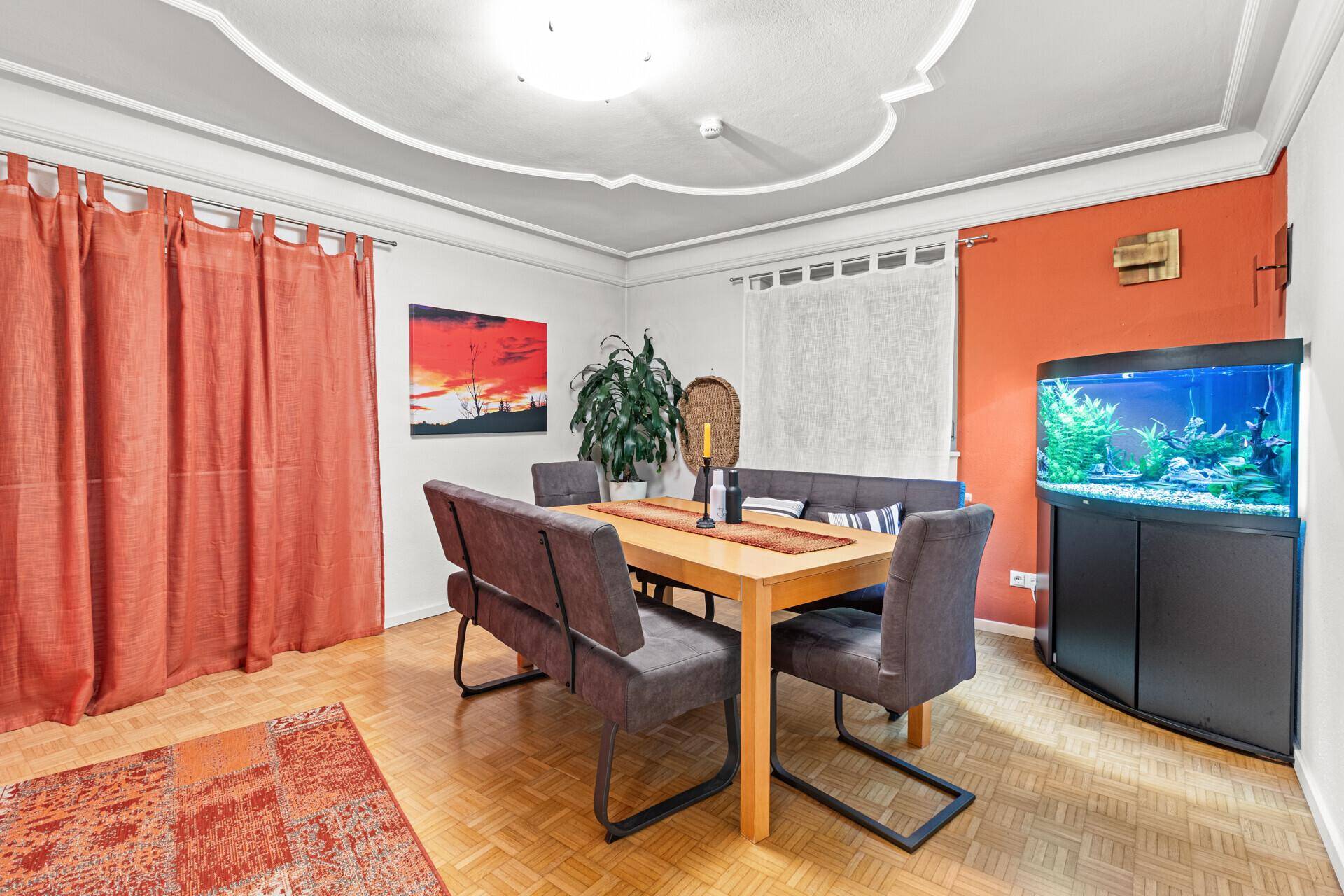 Gemütlicher Essbereich mit Holztisch, Sitzbank und dekorativer Stuckdecke.