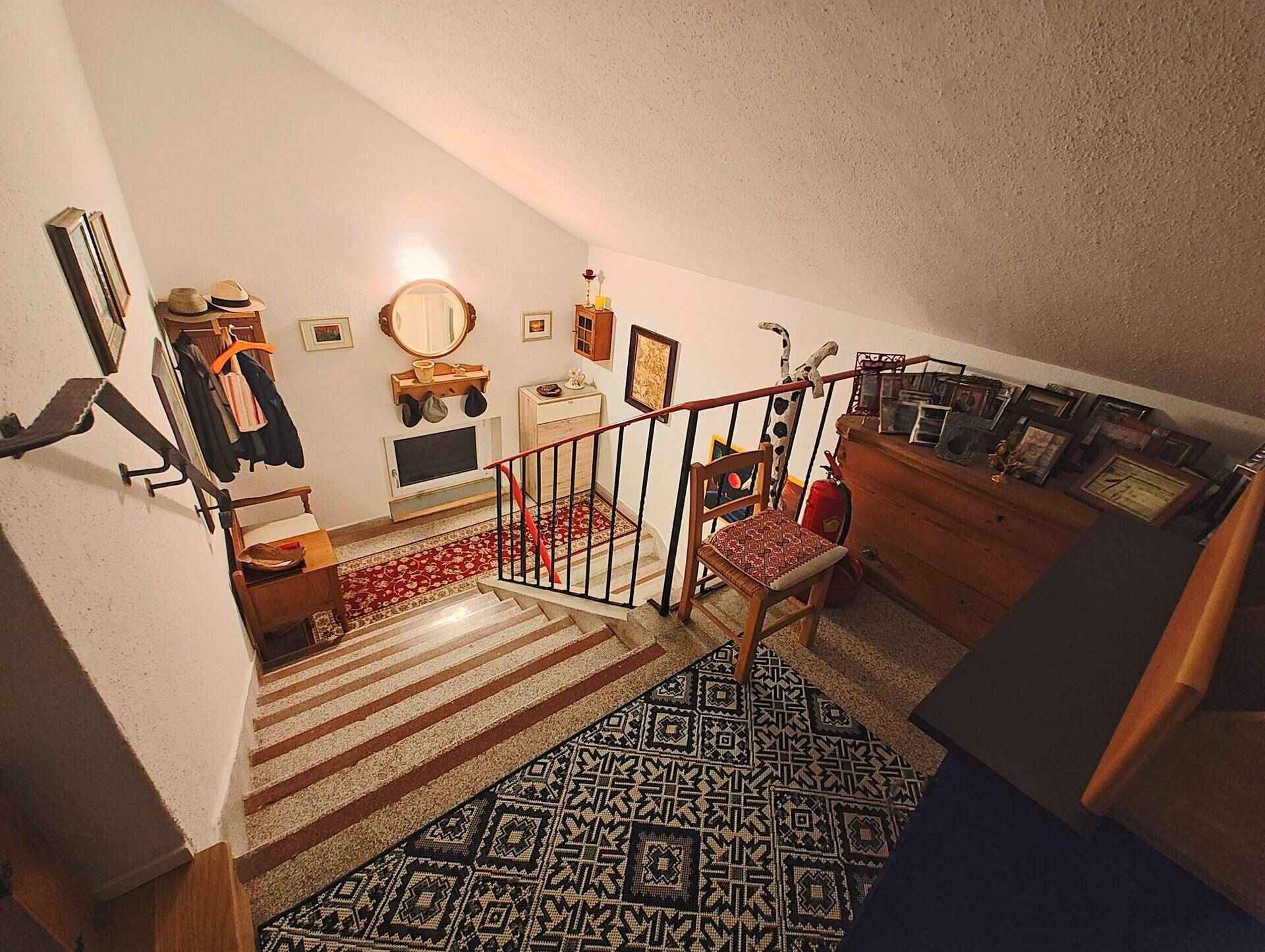 Treppenhaus mit Teppichläufern und dekorativen Elementen an den Wänden.
