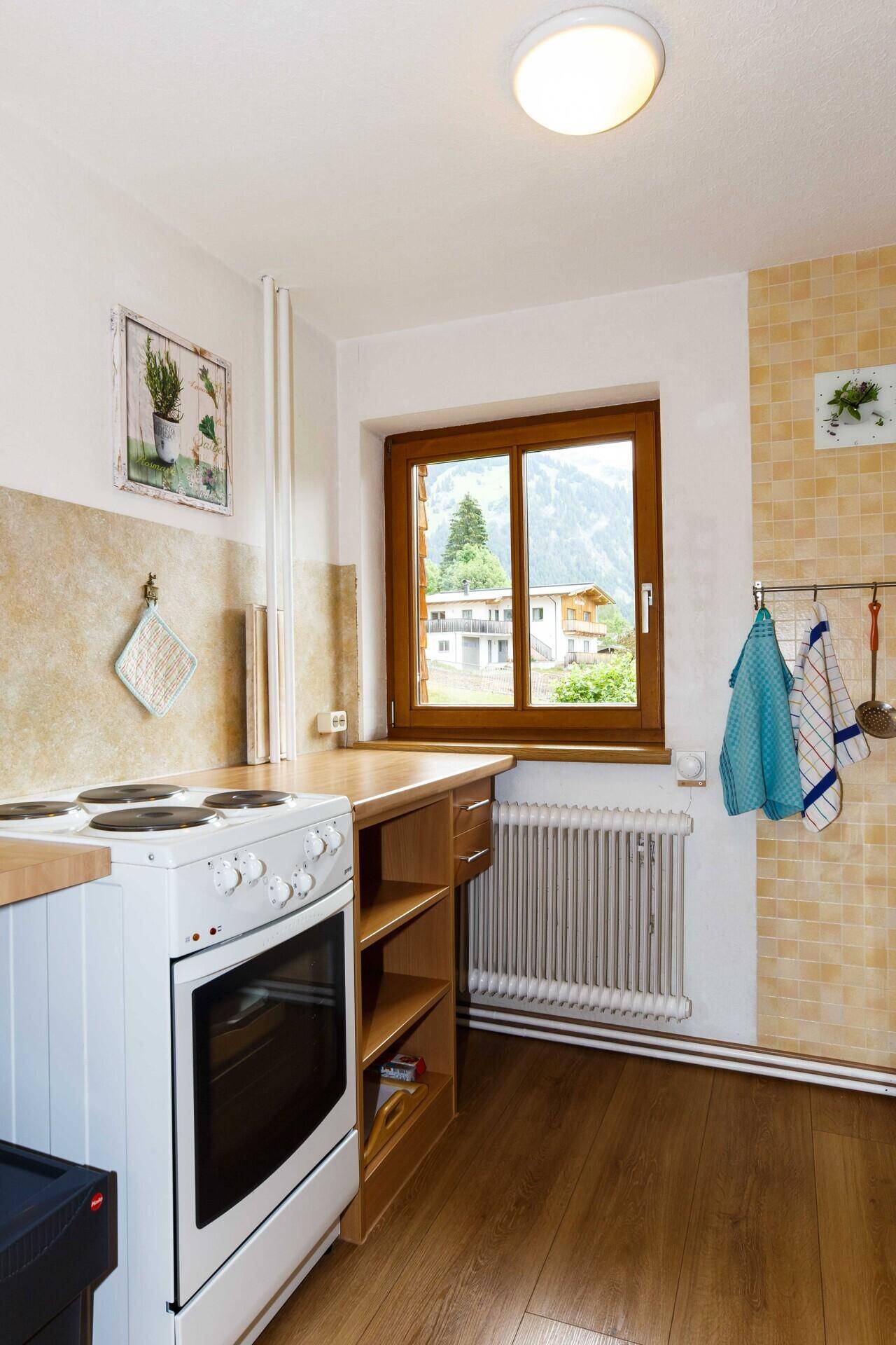 Funktionale Küche mit Herd, Fenster und Blick auf die umliegende Berglandschaft.
